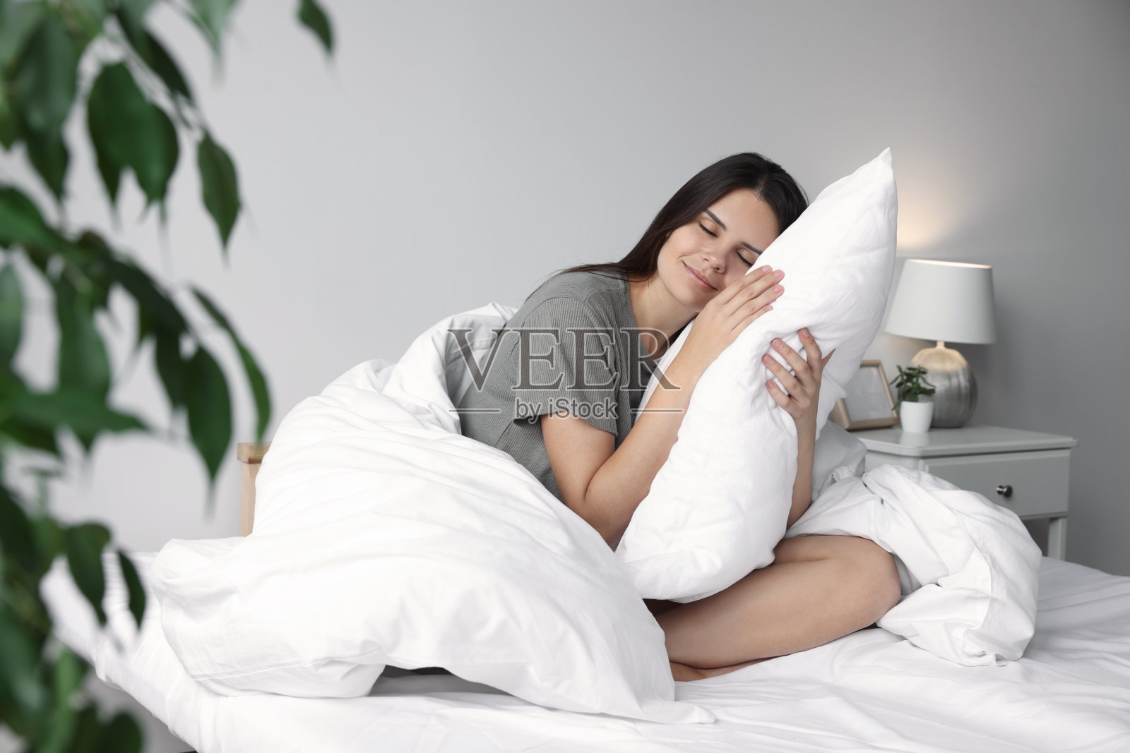 漂亮的年轻女子抱着枕头躺在家里的床上照片摄影图片