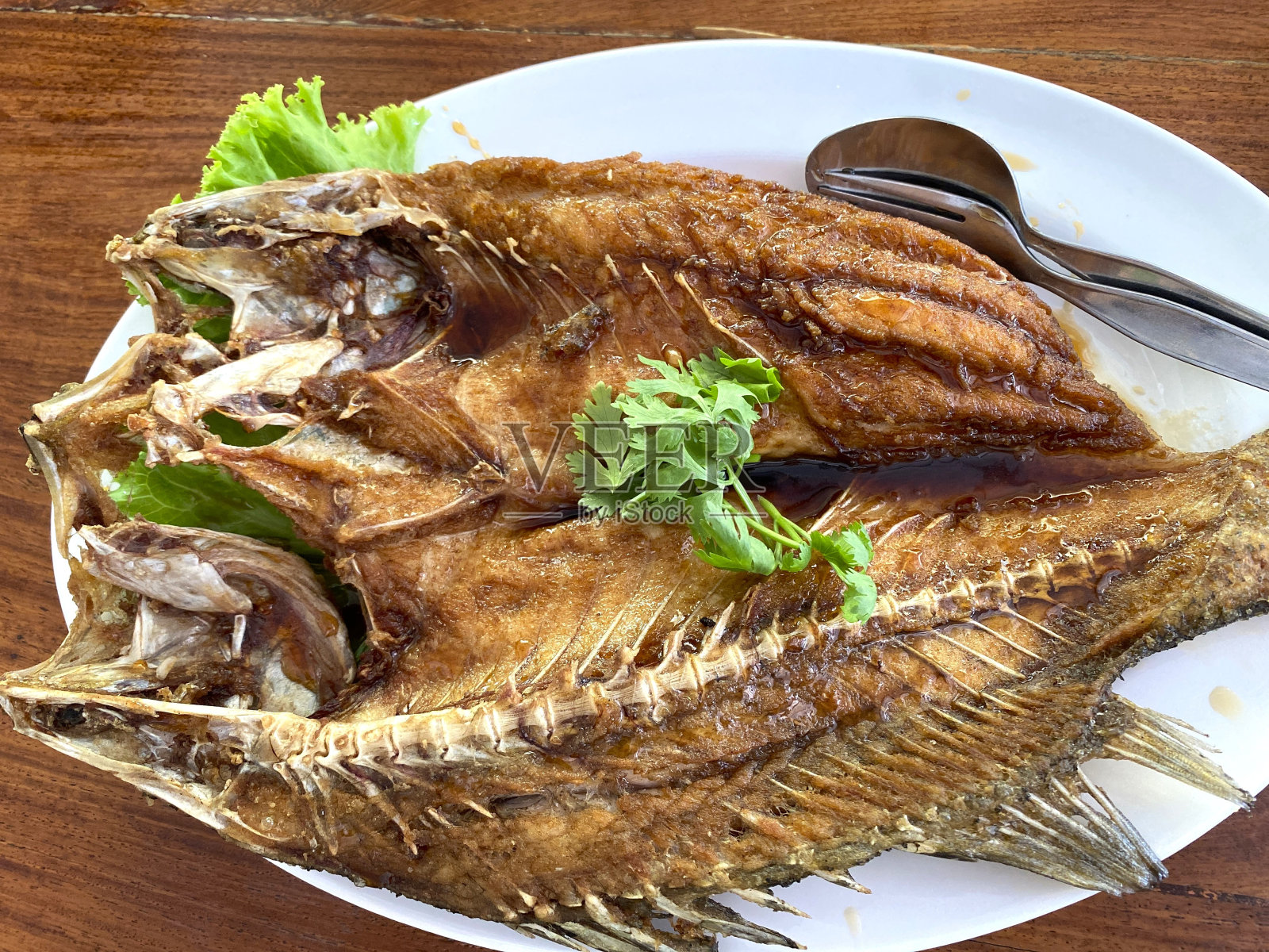 泰国餐厅的鱼露煎鲈鱼。油炸海鲈鱼。照片摄影图片