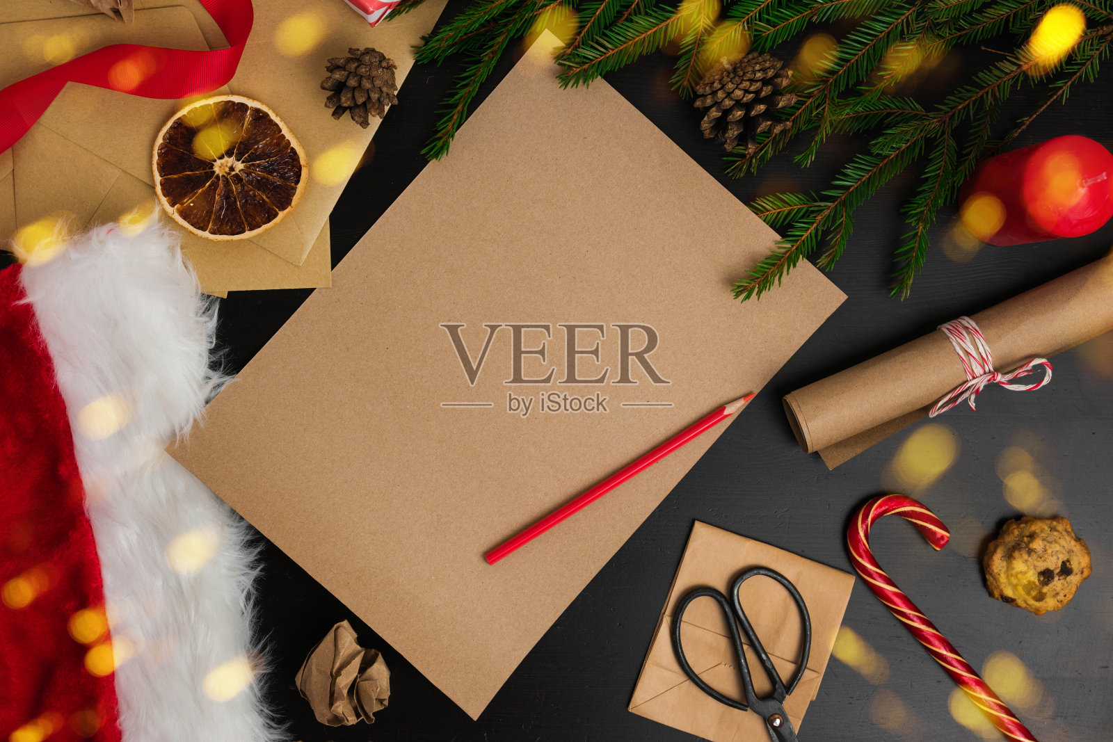 空白的棕色纸页在黑色的木头桌子与圣诞装饰。给圣诞老人的信的模型。俯视图的快乐父亲桌子与信封，冷杉枝，圣诞装饰品。从上面看照片摄影图片