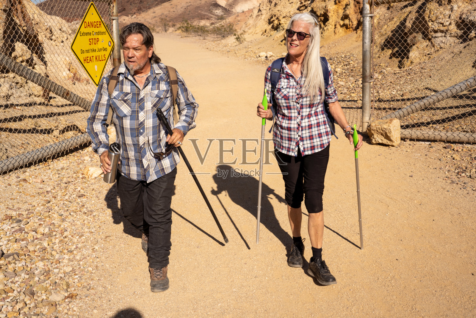 两个高年级学生在阳光明媚的天气里在岩石区徒步旅行。一对旅行者在内华达州研究岩石。照片摄影图片