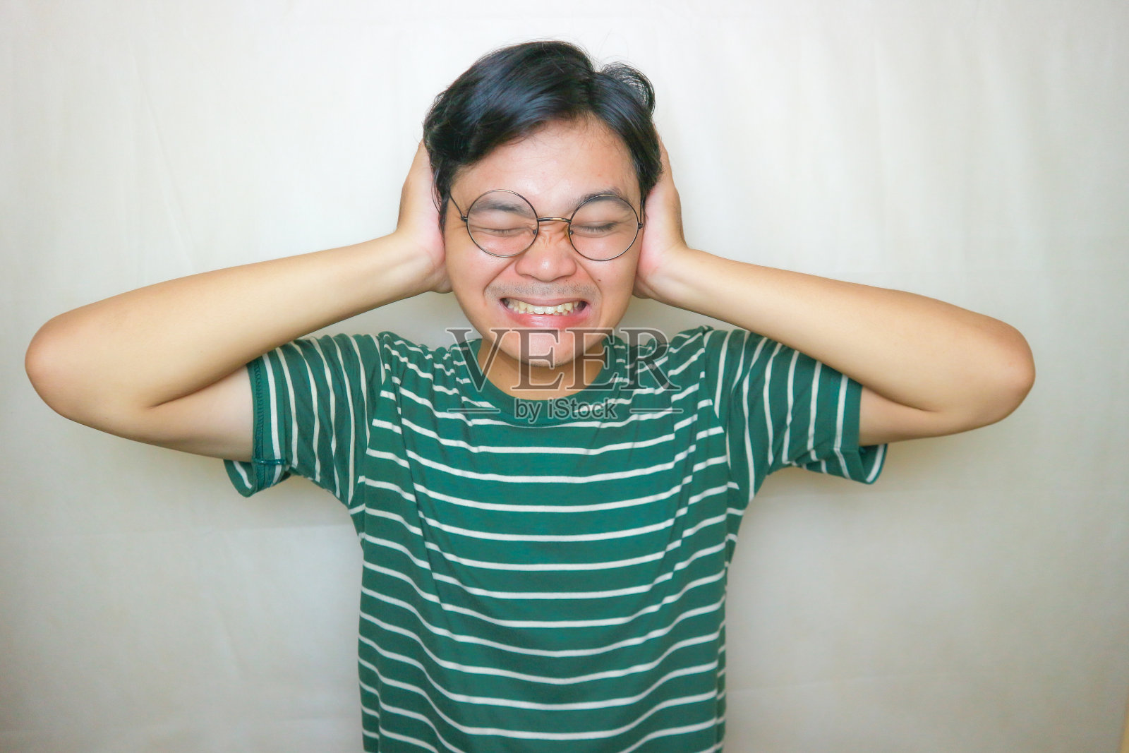 一名印尼亚裔男子身穿绿色衣服，以白色为背景，正在拍摄各种表情的照片照片摄影图片