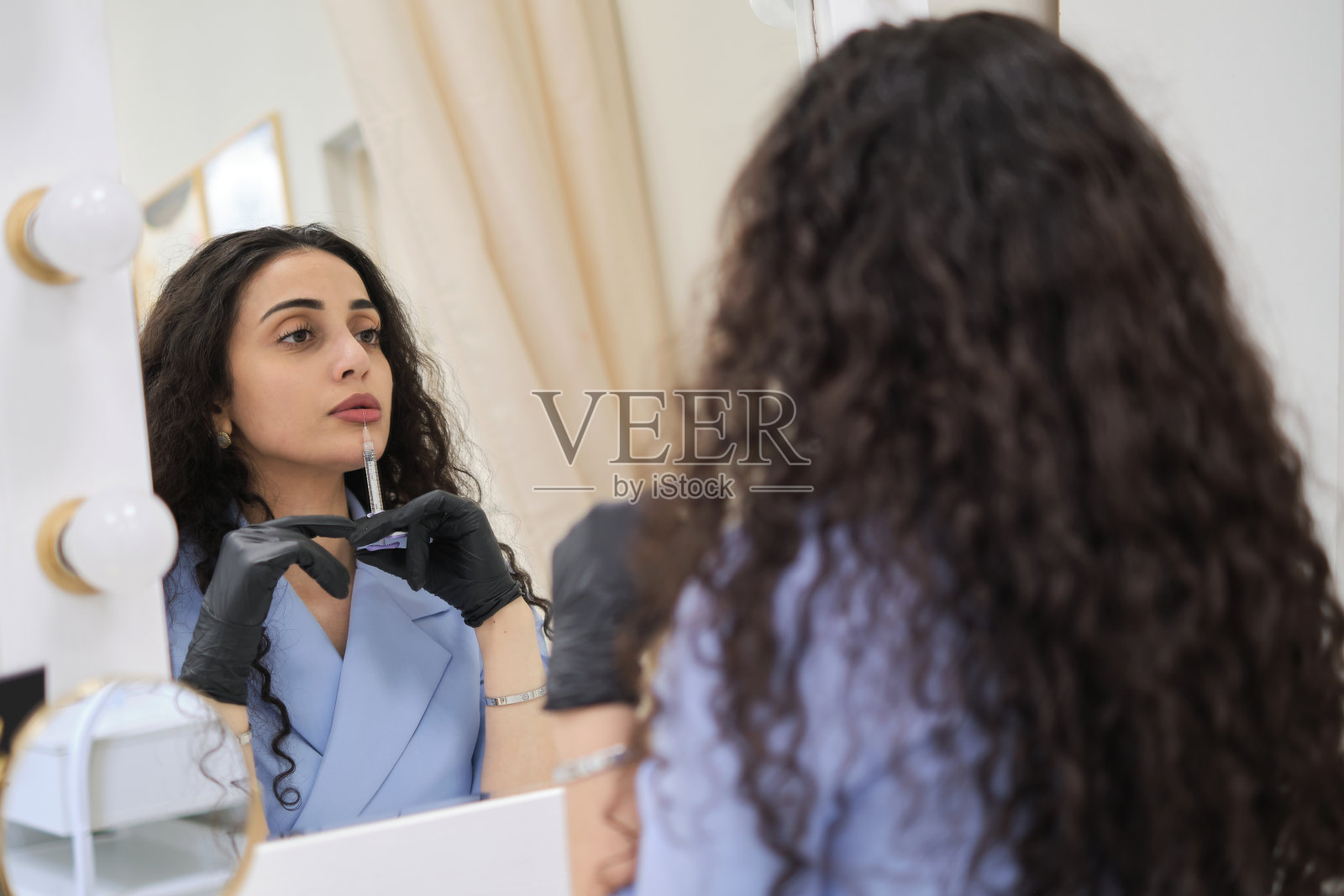 从激情到职业:一位年轻的卷发美容师在她的诊所里反思的时刻，展示了美容和健康领域所需要的奉献和激情的深度。照片摄影图片