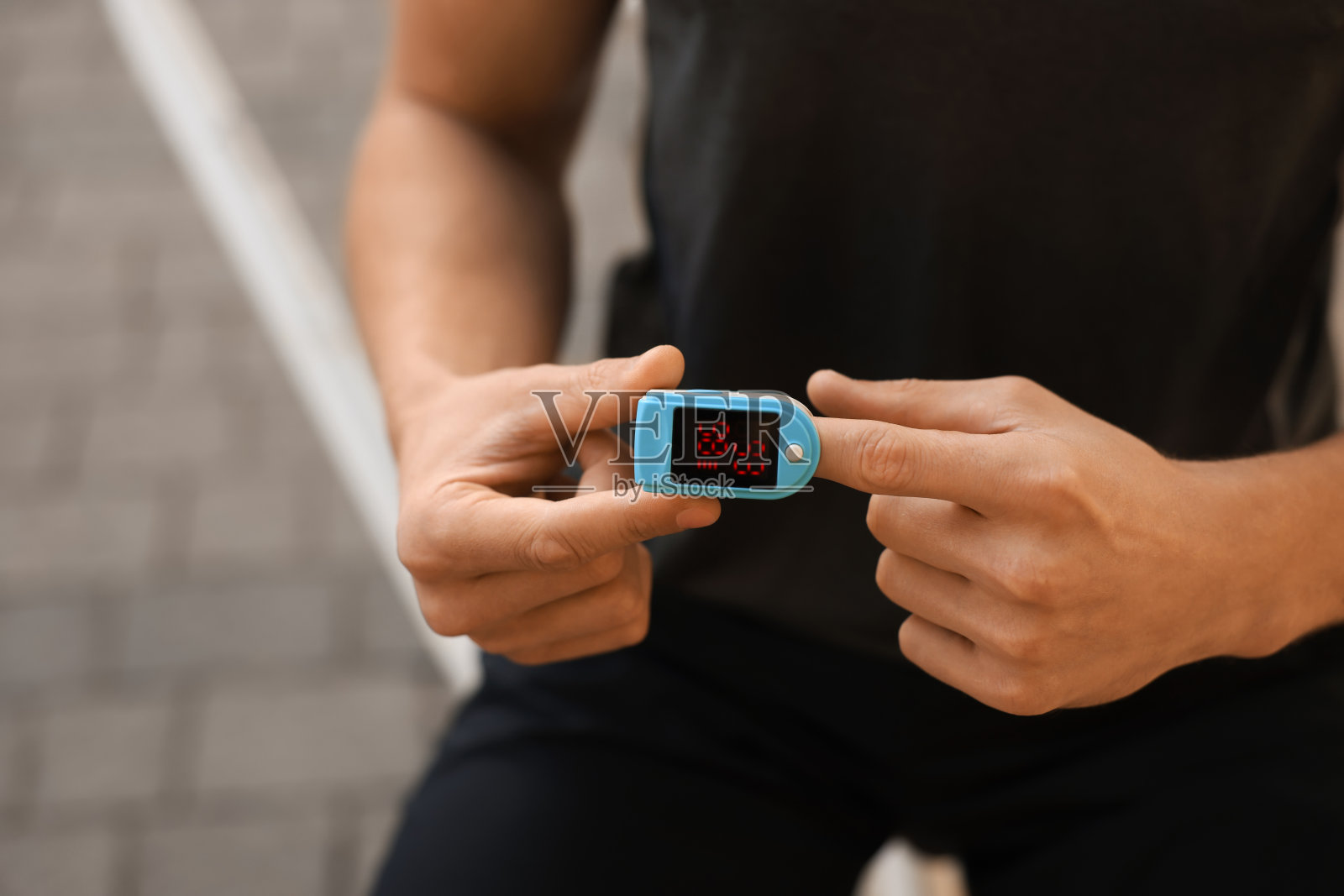 男子在户外训练后用手指上的血压计检查脉搏，特写。文本空间照片摄影图片