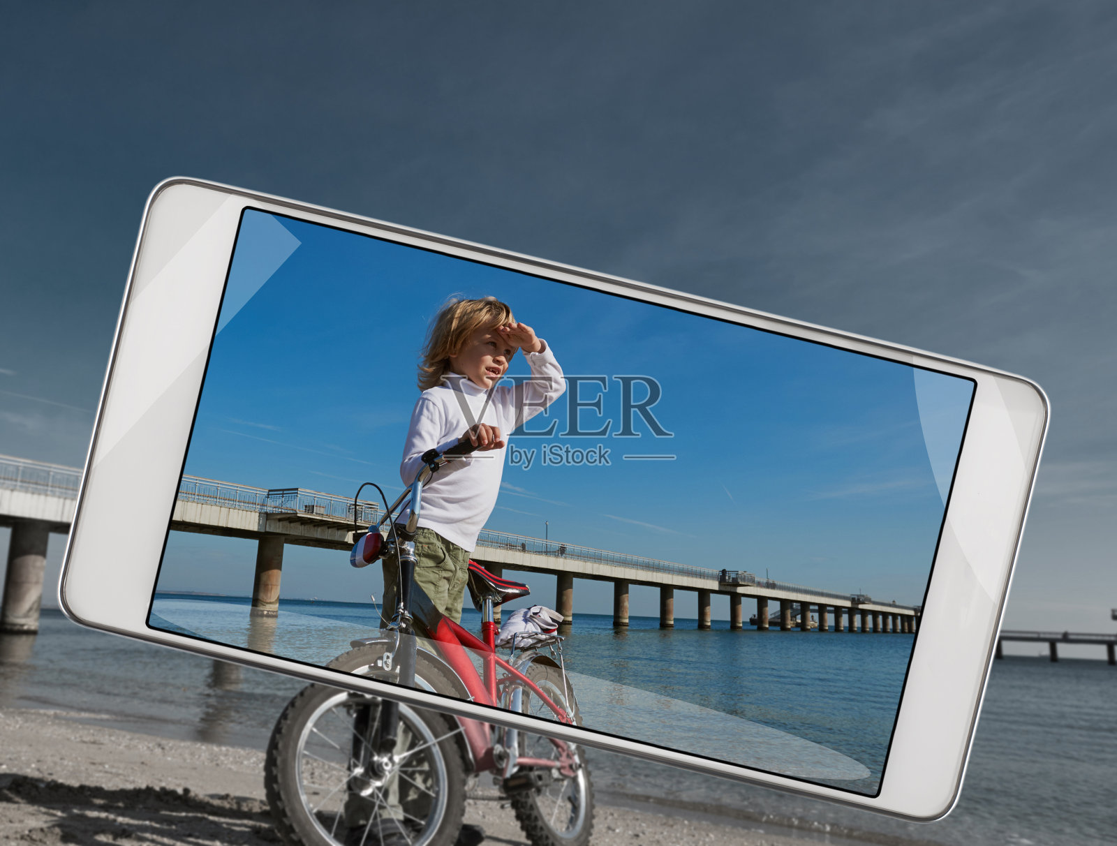 男孩在海边骑自行车玩智能手机照片摄影图片