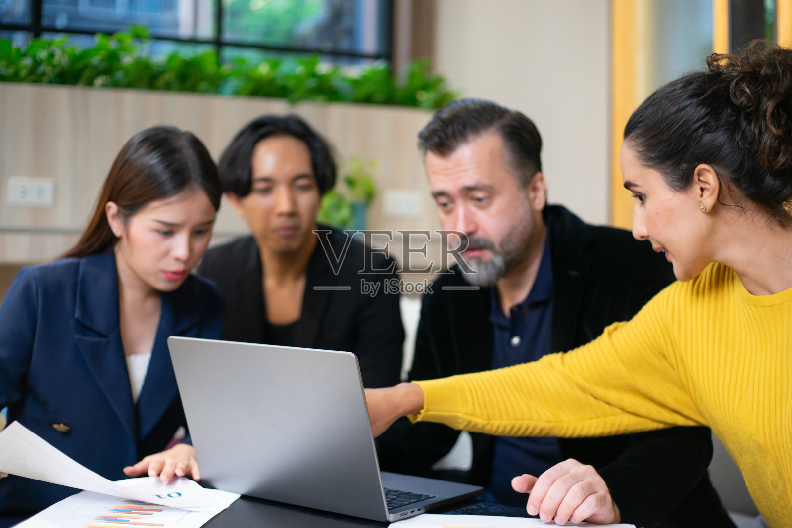 在头脑风暴期间，一群不同的员工、商业人士组成的团队。他们正在讨论新项目的新想法。多种族的同事在办公室的生活空间里用笔记本电脑和文件表工作。照片摄影图片