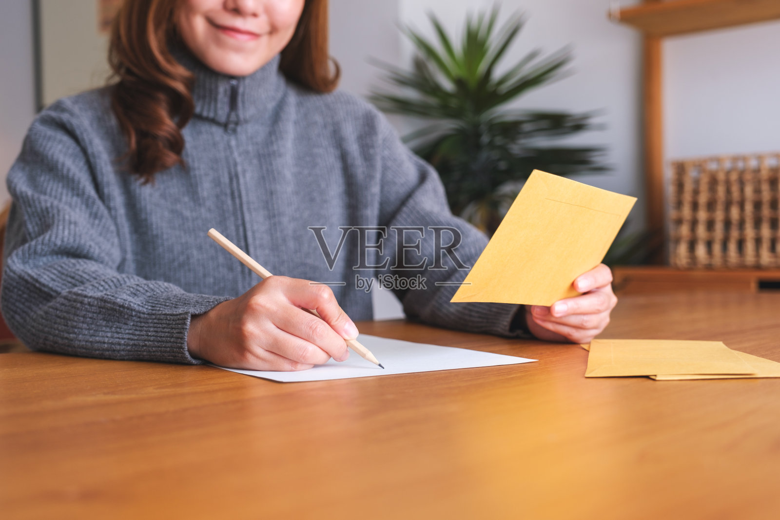 一个年轻女子在信和信封上写字的特写照片摄影图片