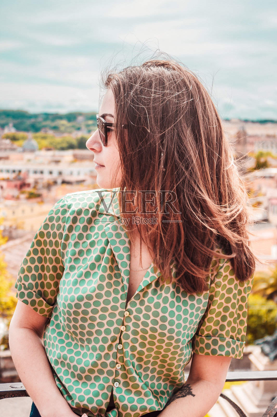 年轻女子的侧面肖像，戴着墨镜，带着罗马全景。在意大利度假的女孩。南欧晴朗的一天。照片摄影图片