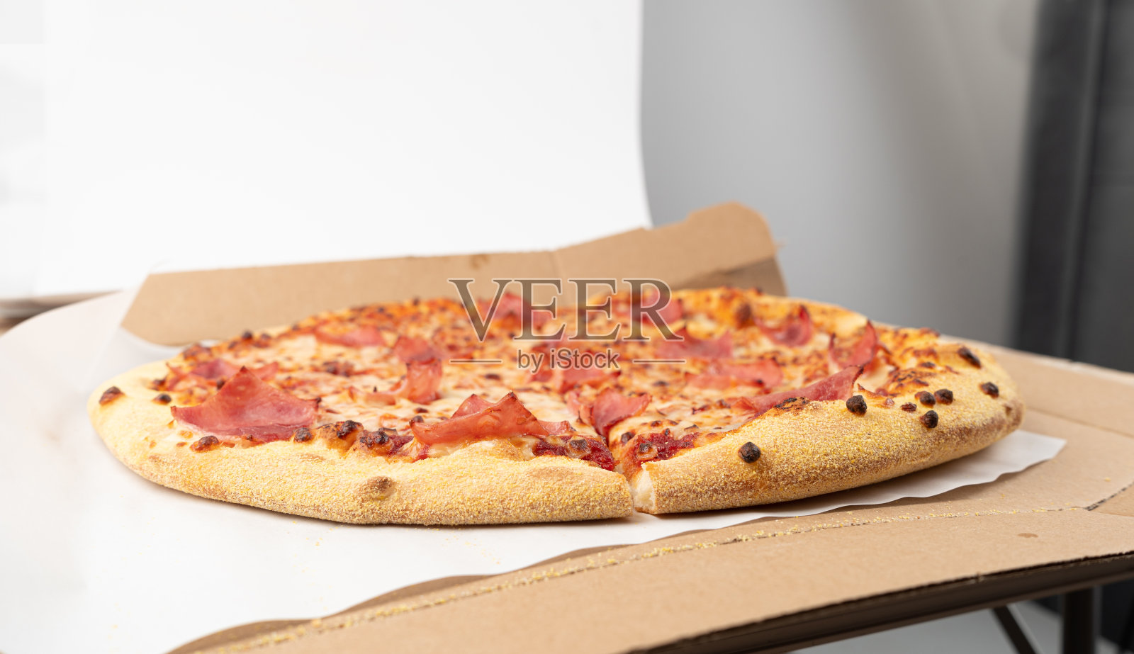 采购产品意大利披萨在纸板箱，火腿披萨与绿辣椒，辣椒和马苏里拉奶酪照片摄影图片