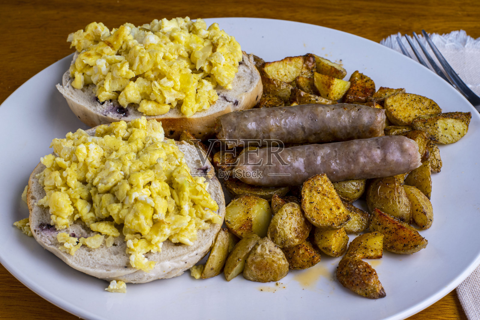 在百吉饼上炒鸡蛋，配上家庭炸薯条照片摄影图片