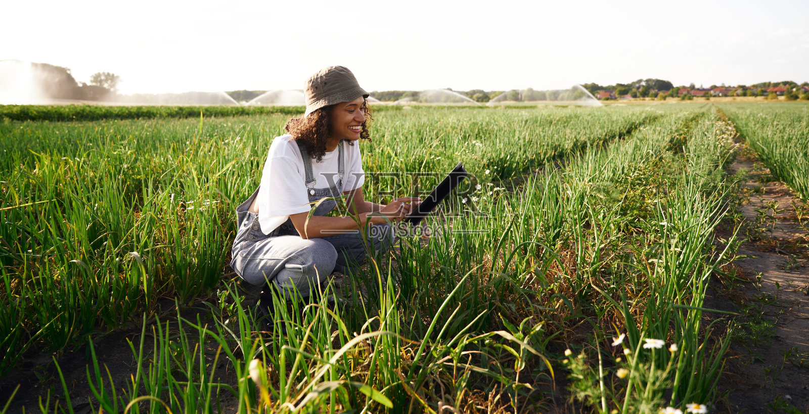 微笑的女农民站在田地里摆弄数码平板电脑。农业经营理念照片摄影图片