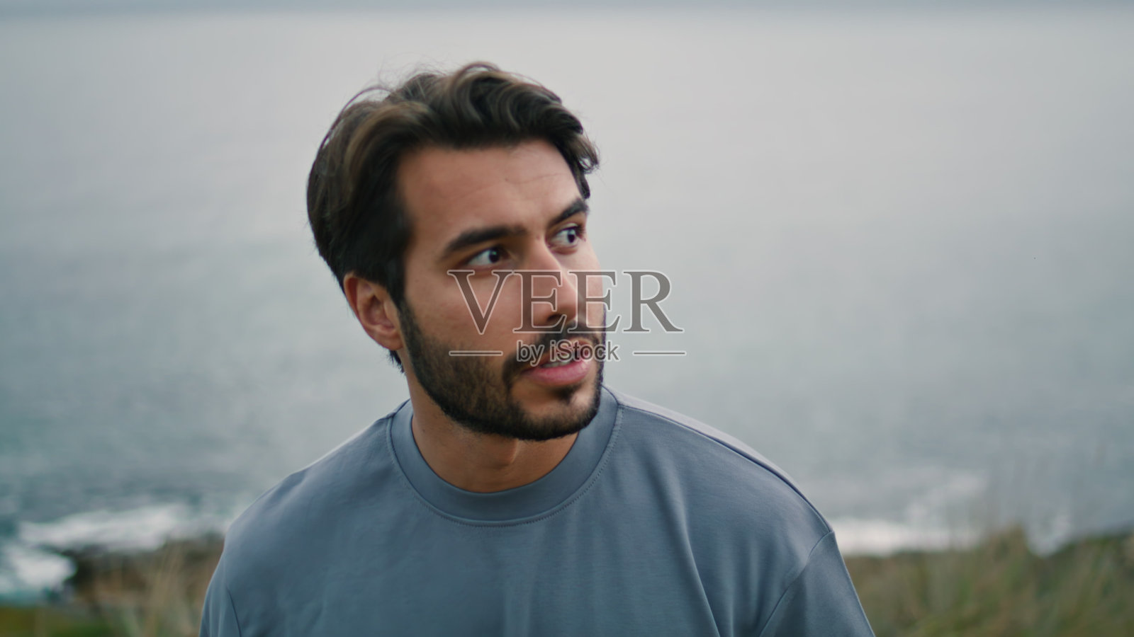 大胡子男子独自走在阴暗的海边。帅哥享受周末。照片摄影图片