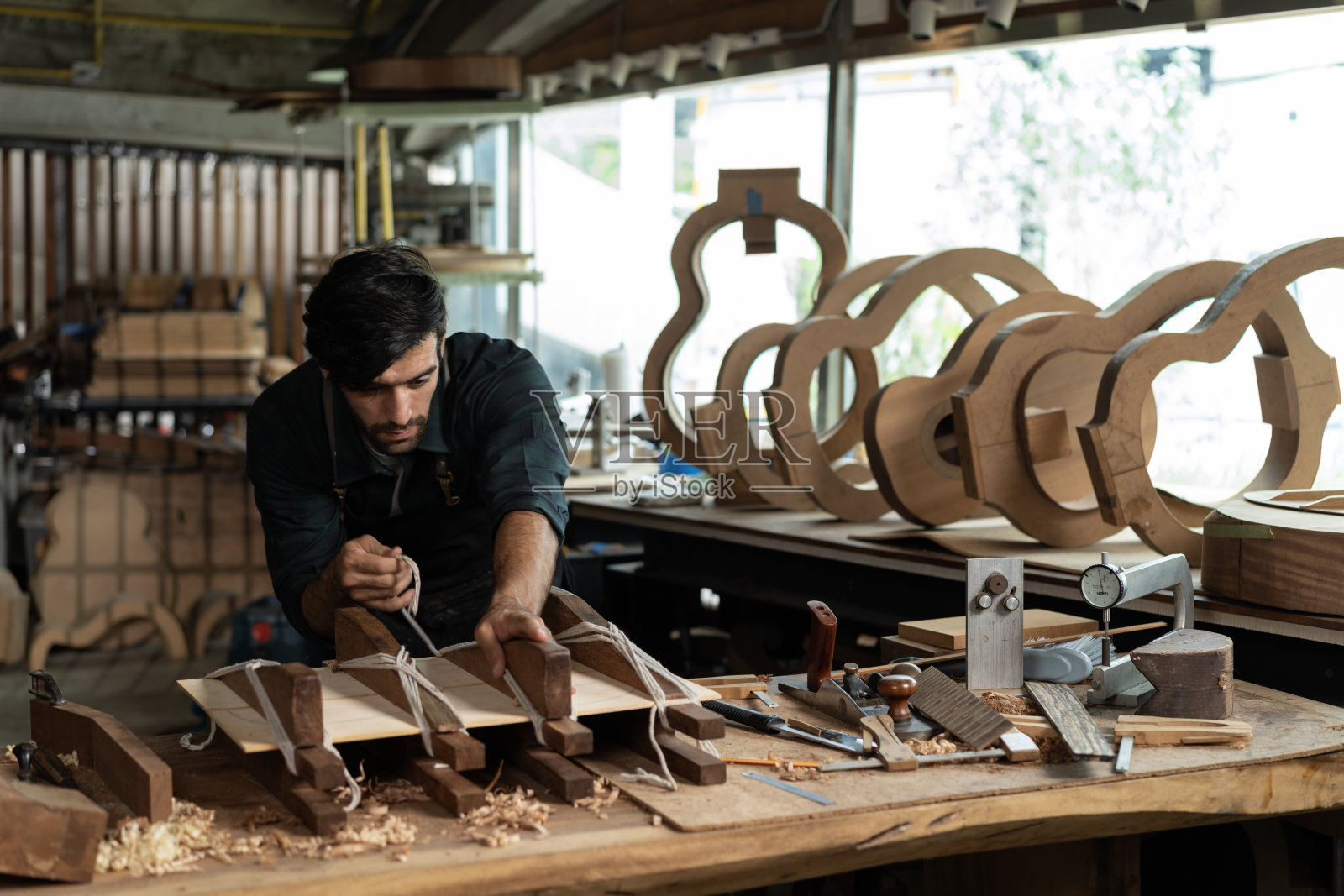 吉他制琴师系绳子，把楔子插到云杉木板上照片摄影图片