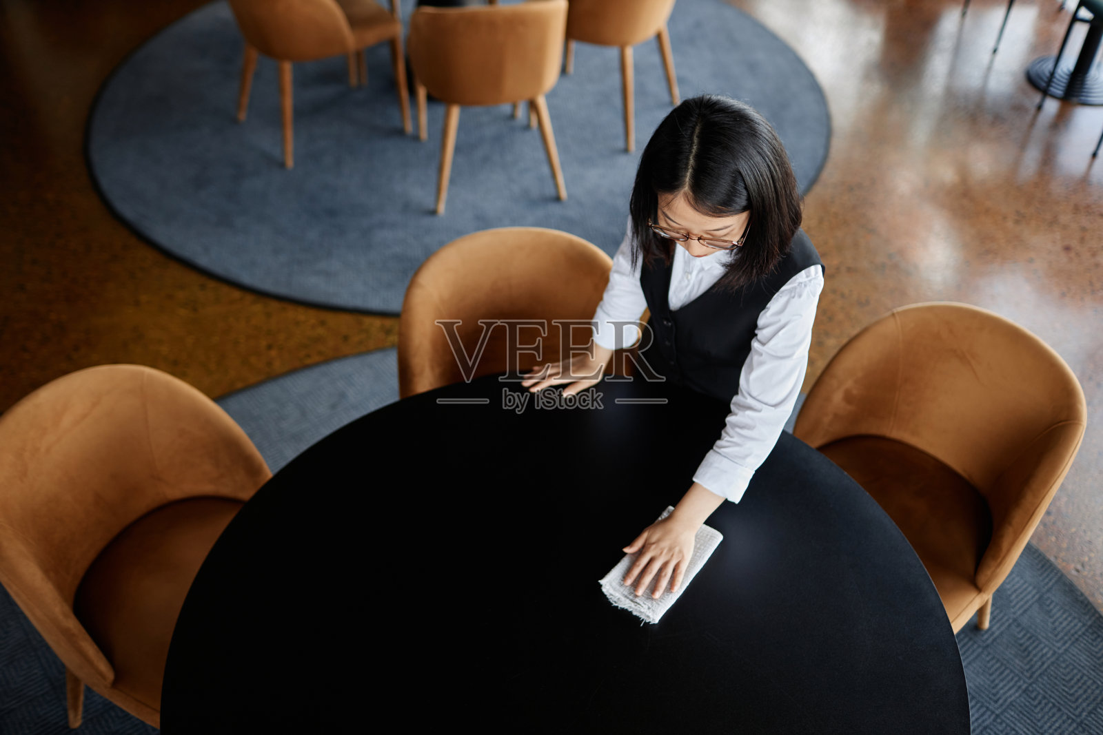 在准备开业的餐馆里擦拭餐桌的妇女照片摄影图片