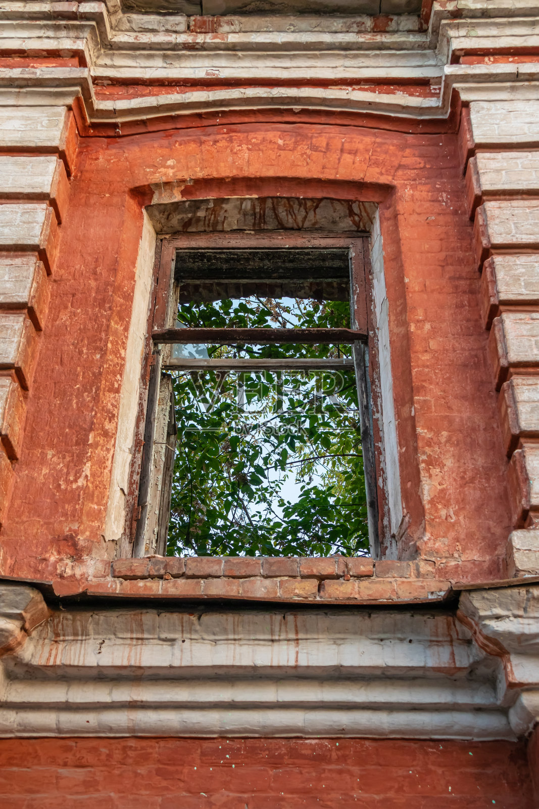 一座废弃建筑外立面的砖墙上，没有玻璃的木框窗户。没有屋顶的房子照片摄影图片