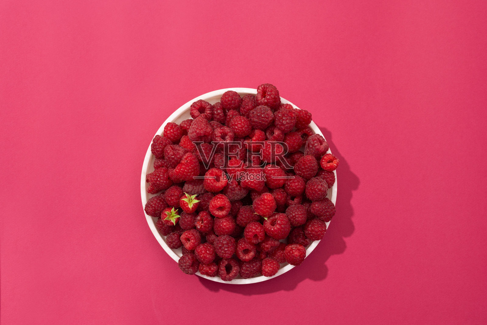 盘新鲜的覆盆子在白色，粉红色和绿色的背景照片摄影图片