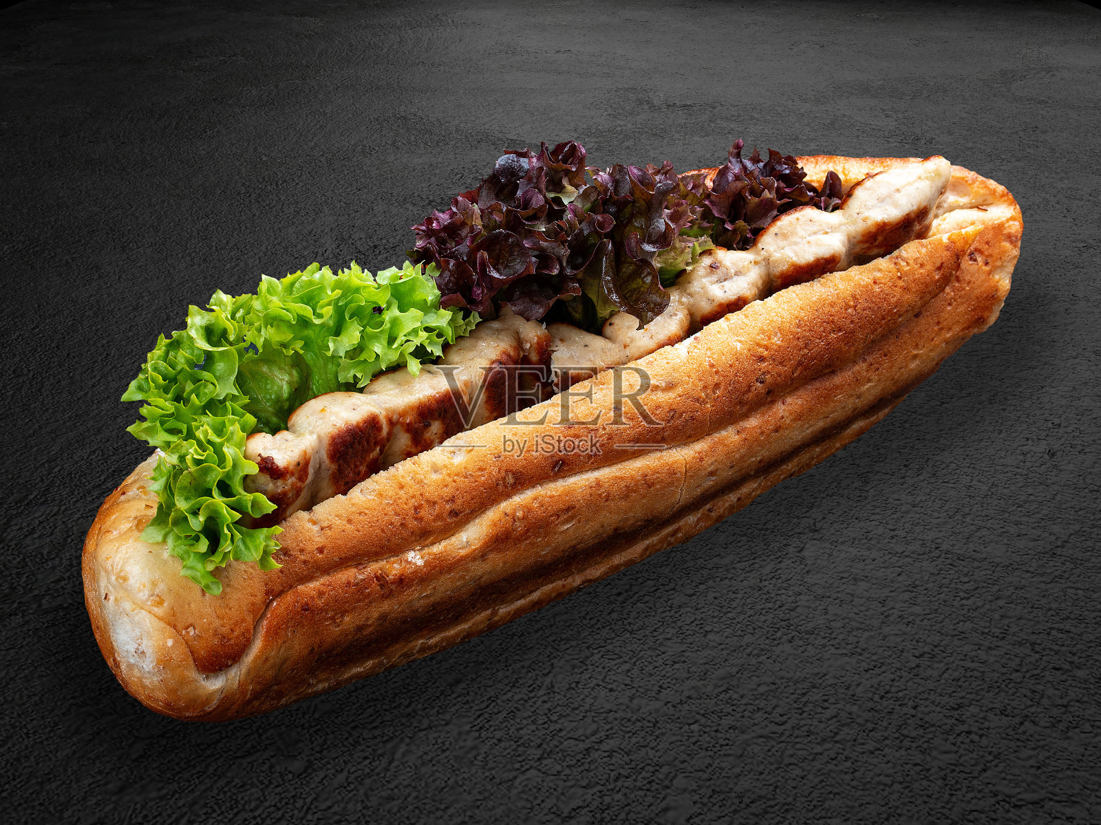 烤鸡串夹在面包里，配上生菜和酱汁。孤立在黑暗的背景上照片摄影图片