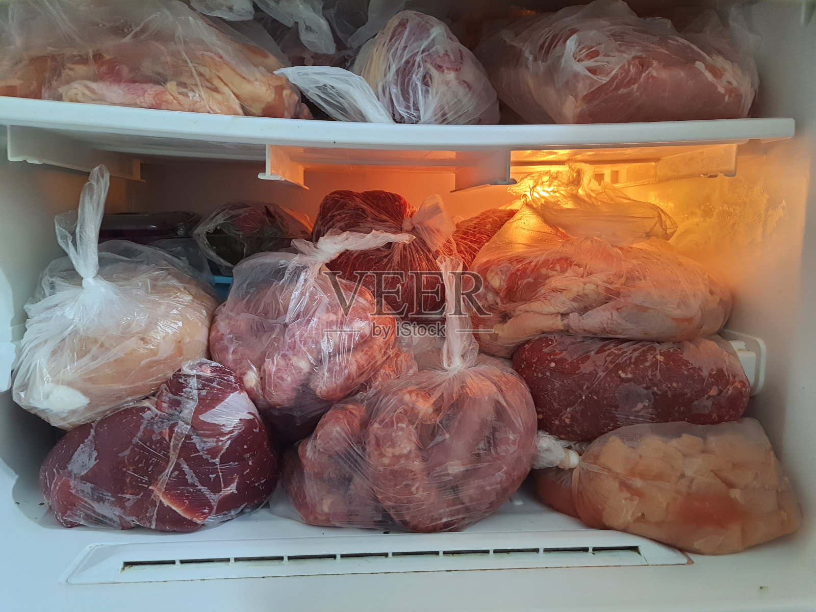 家用冷冻机备有各类肉类:鸡肉、香肠、红肉。前视图。照片摄影图片