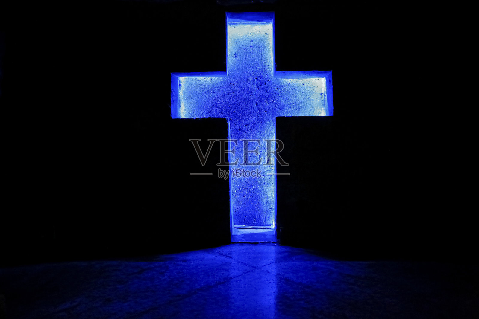 独立的蓝色照亮石十字架在著名的地下盐大教堂的济帕奎拉与反射和黑暗的背景，哥伦比亚照片摄影图片
