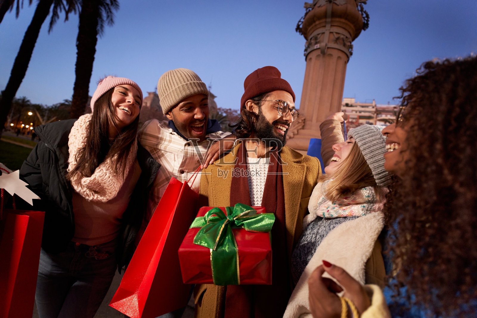 兴奋微笑的多民族人群手持五颜六色的购物袋赠送礼物。笑着年轻。照片摄影图片