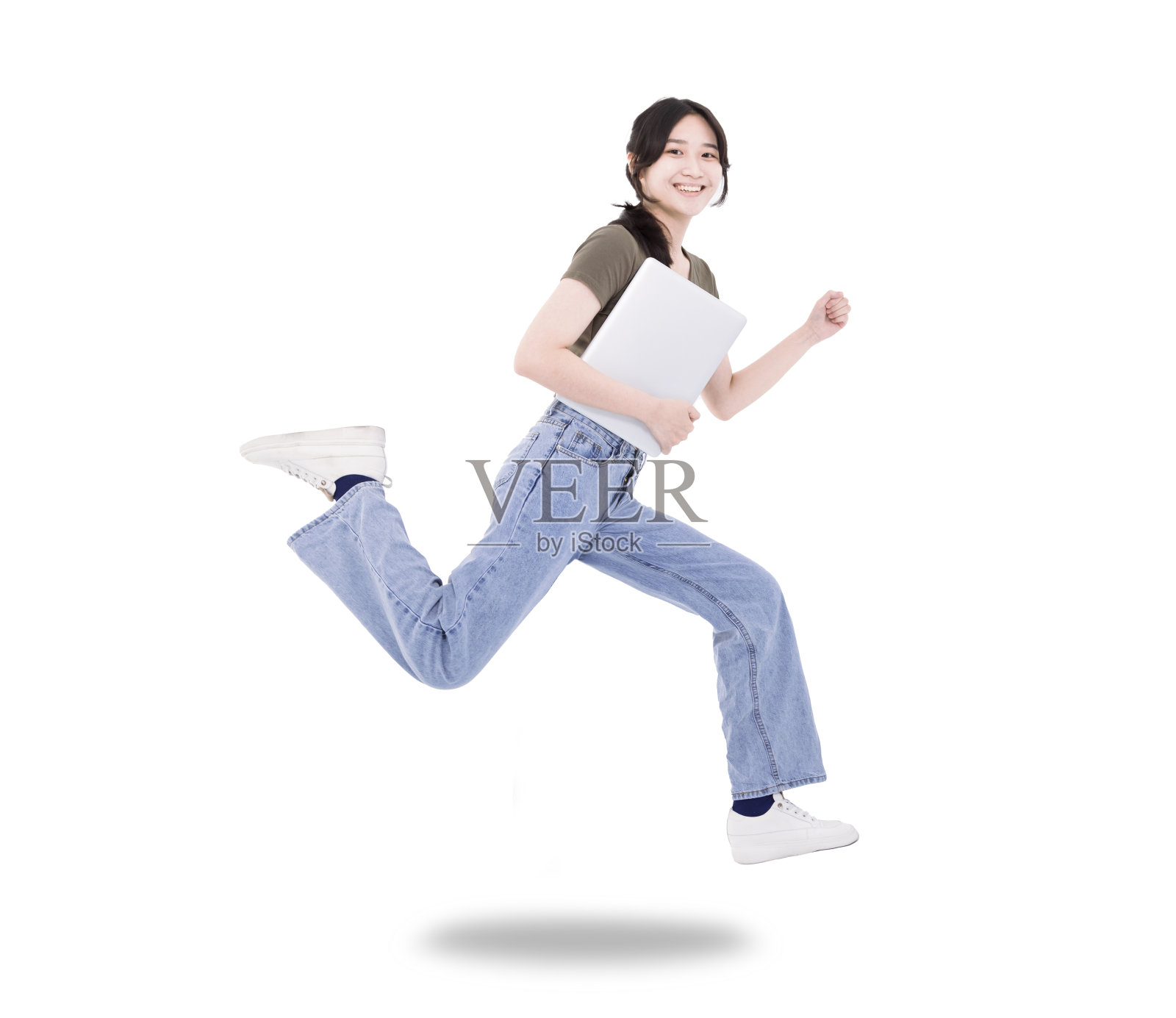 快乐的女学生拿着笔记本电脑跳和跑穿t恤牛仔孤立的白色背景照片摄影图片