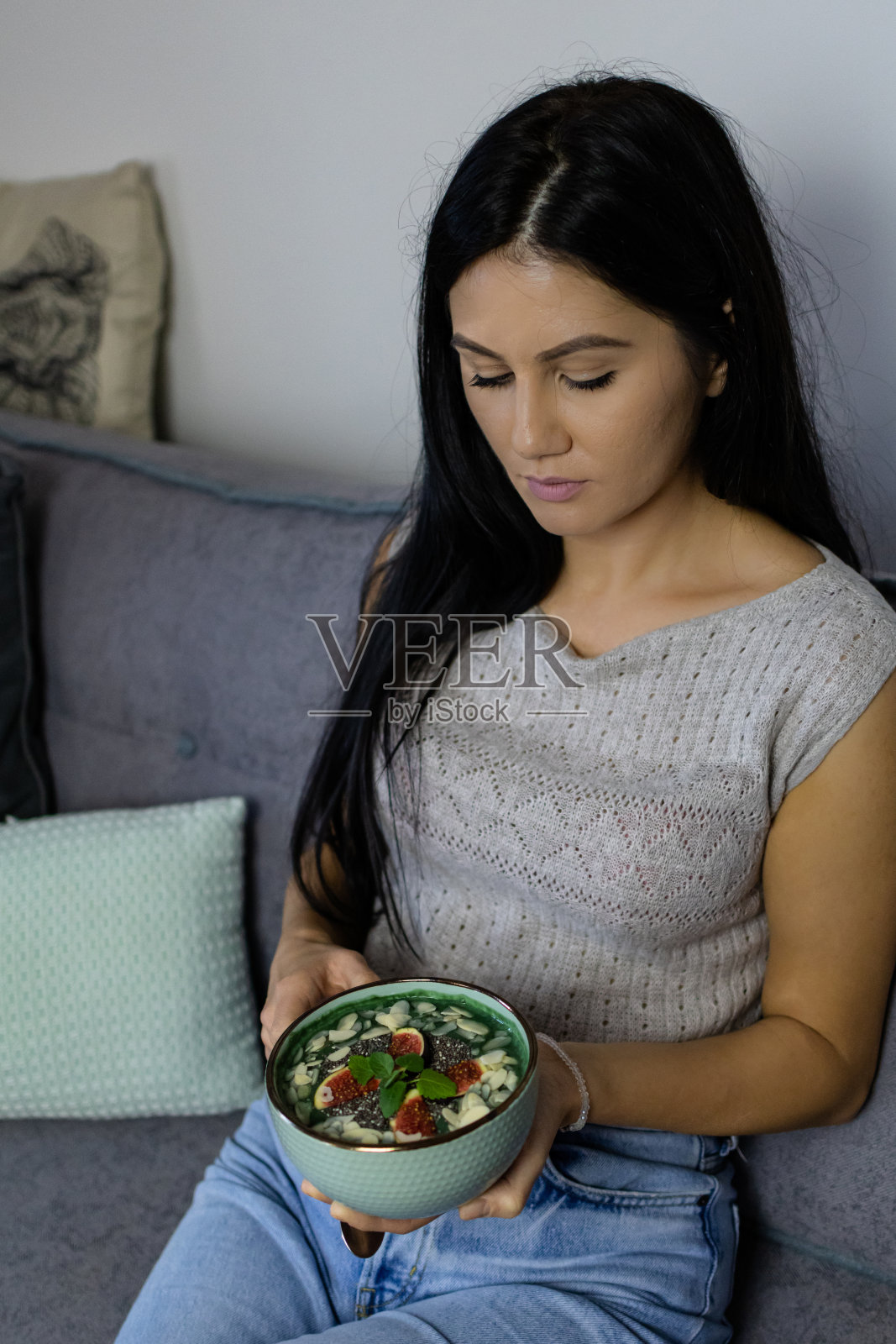 美丽的女人正在吃健康的素食排毒绿色奶昔在一个碗里，螺旋藻或小球藻。排毒、减肥、健康饮食、饮食理念。照片摄影图片