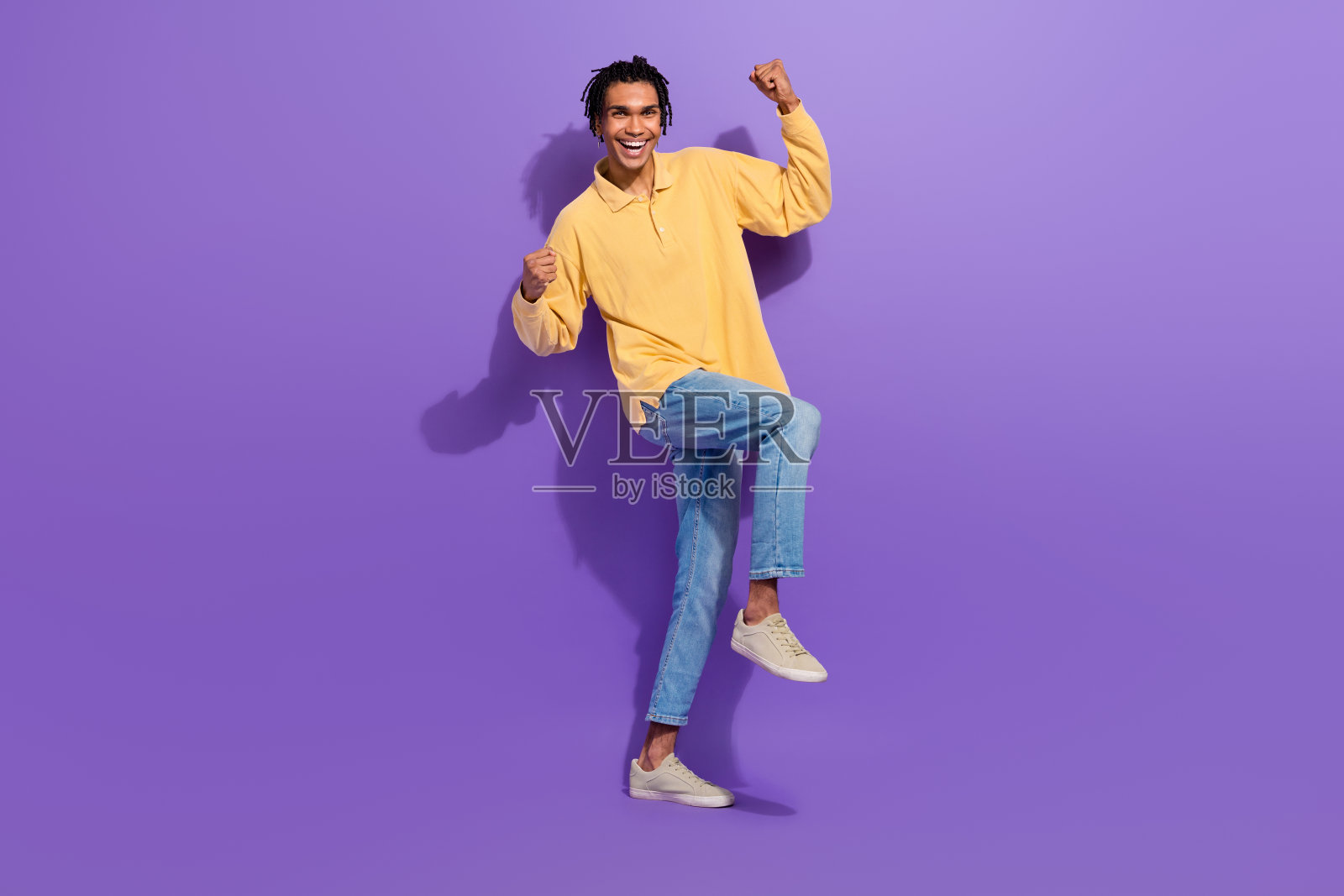 身长干部的无忧青年小伙举起拳头欢呼胜利冠军奖杯头奖孤立在紫色的背景上照片摄影图片