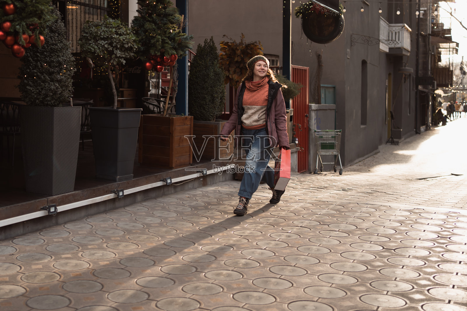 漂亮的成年女子带着礼物袋走在装饰得很漂亮的圣诞街道上照片摄影图片