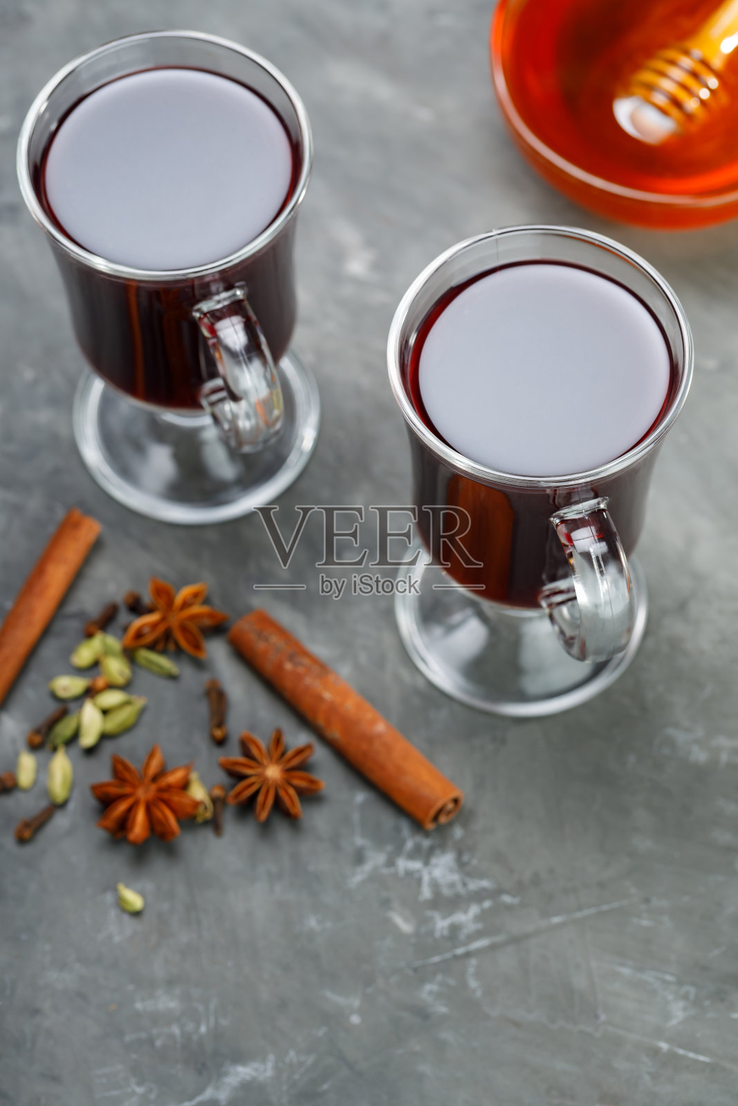 两杯在混凝土背景上加了蜂蜜和香料的热葡萄酒。本空间照片摄影图片