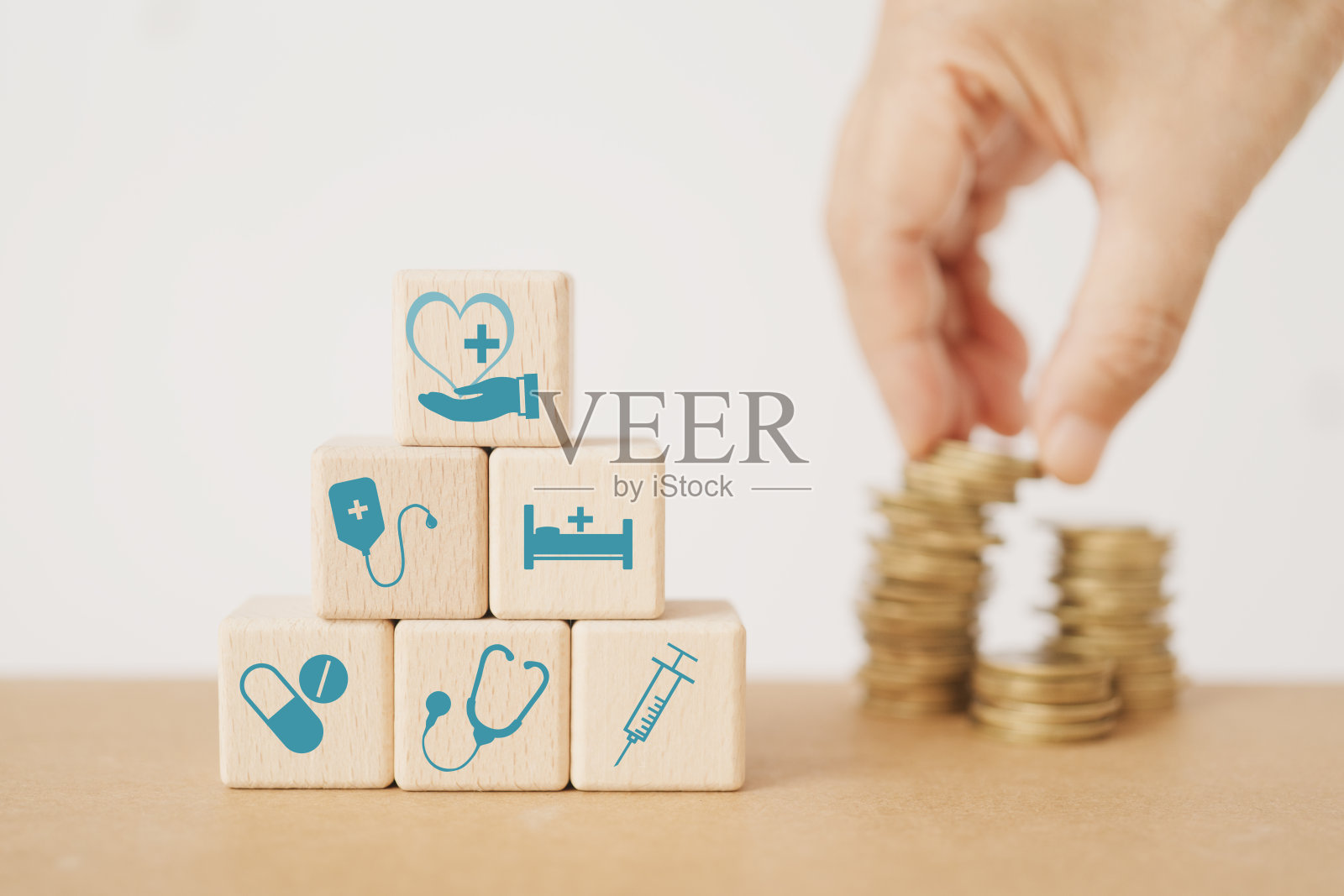 木质立方体块与医疗保健图标，模糊的手和一堆硬币的健康保险，健康，幸福的概念照片摄影图片