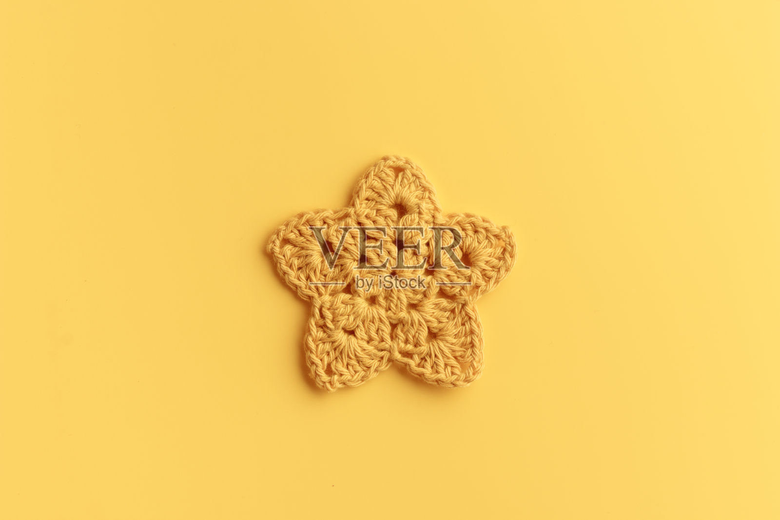 黄色背景上的黄色钩织星星。照片摄影图片