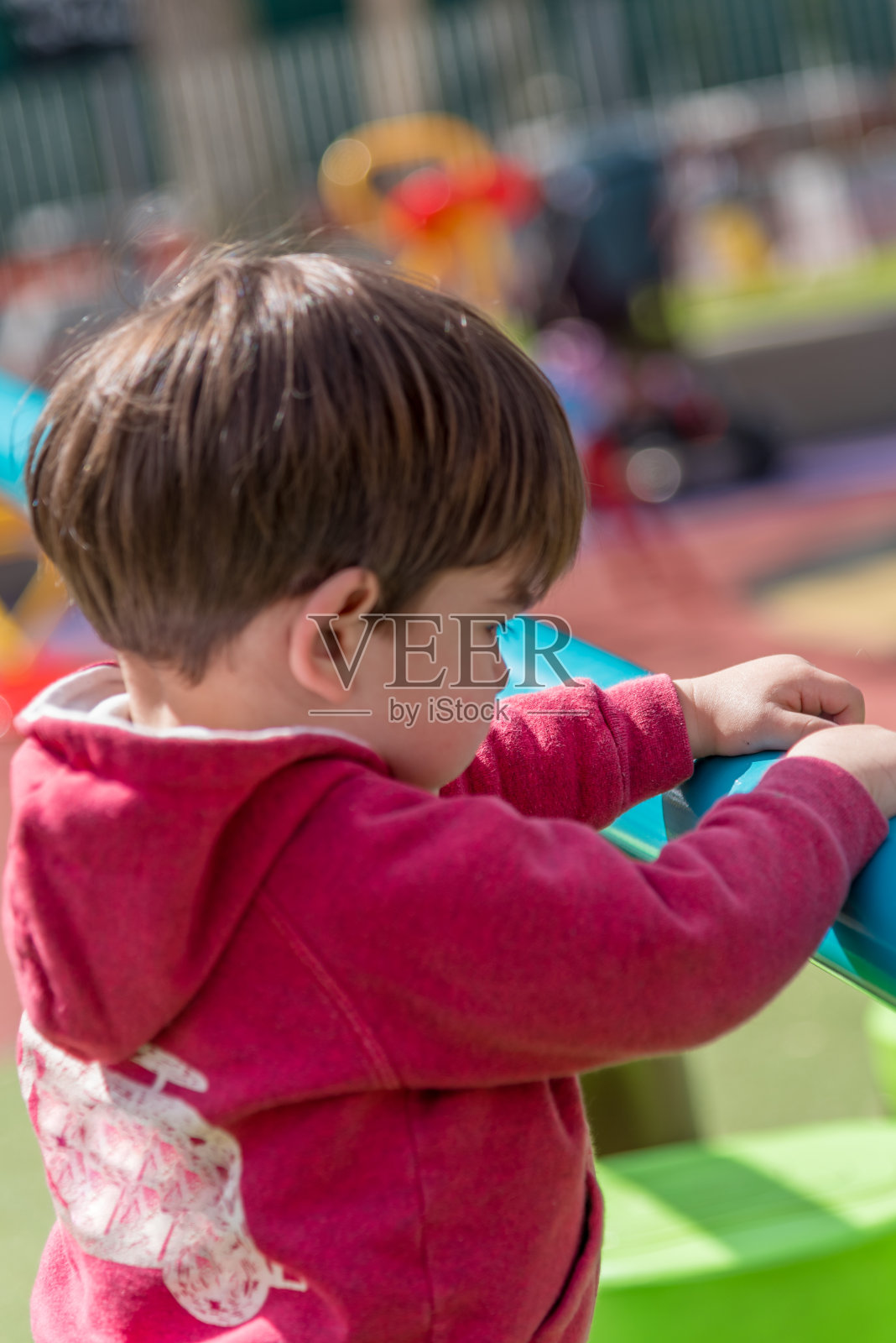 一个小孩子在公园的操场上玩耍。照片摄影图片