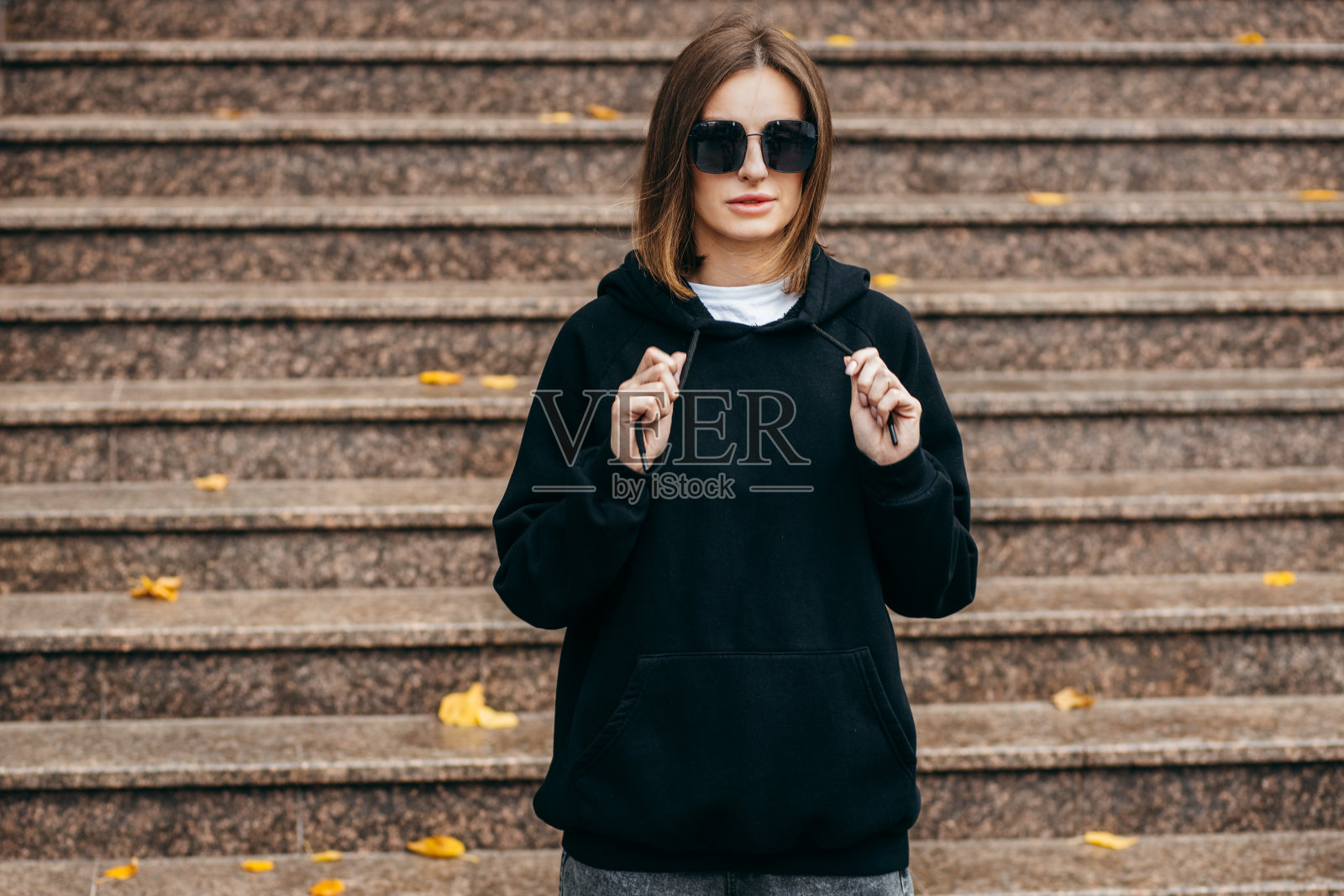 戴眼镜，穿黑色连帽衫的年轻女子照片摄影图片