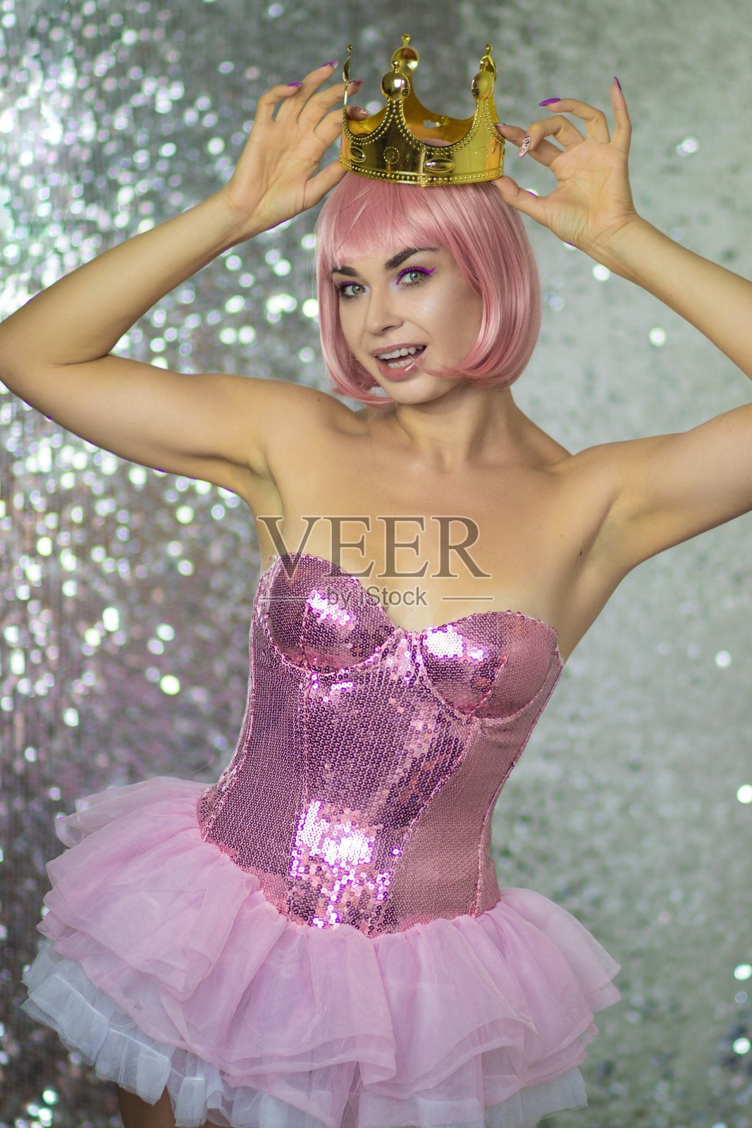 戴着金色皇冠的粉色假发的女人。万圣节照片摄影图片