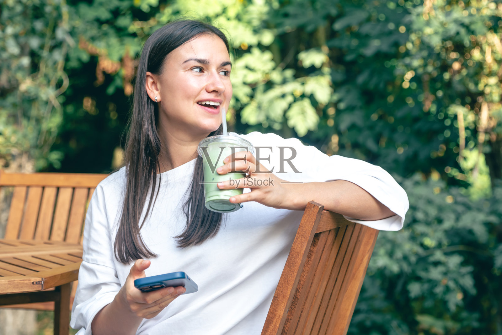 一名女子在咖啡馆喝抹茶拿铁咖啡并使用智能手机照片摄影图片
