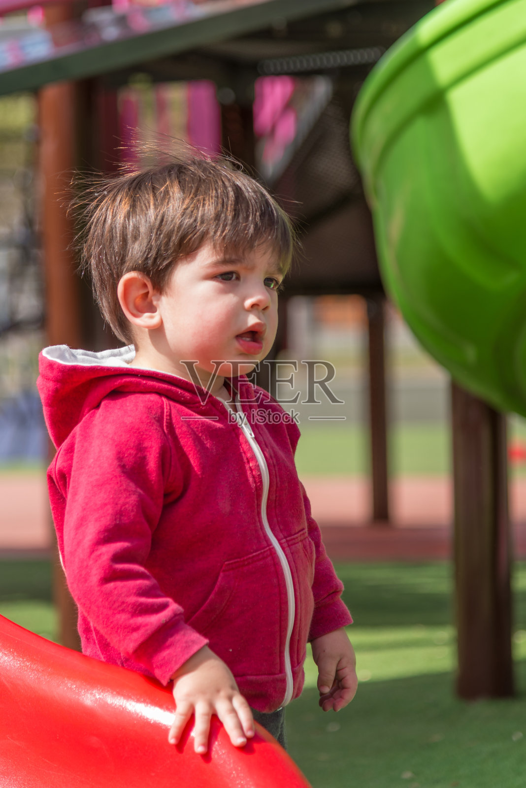 站在操场上的小男孩看起来很困惑。照片摄影图片