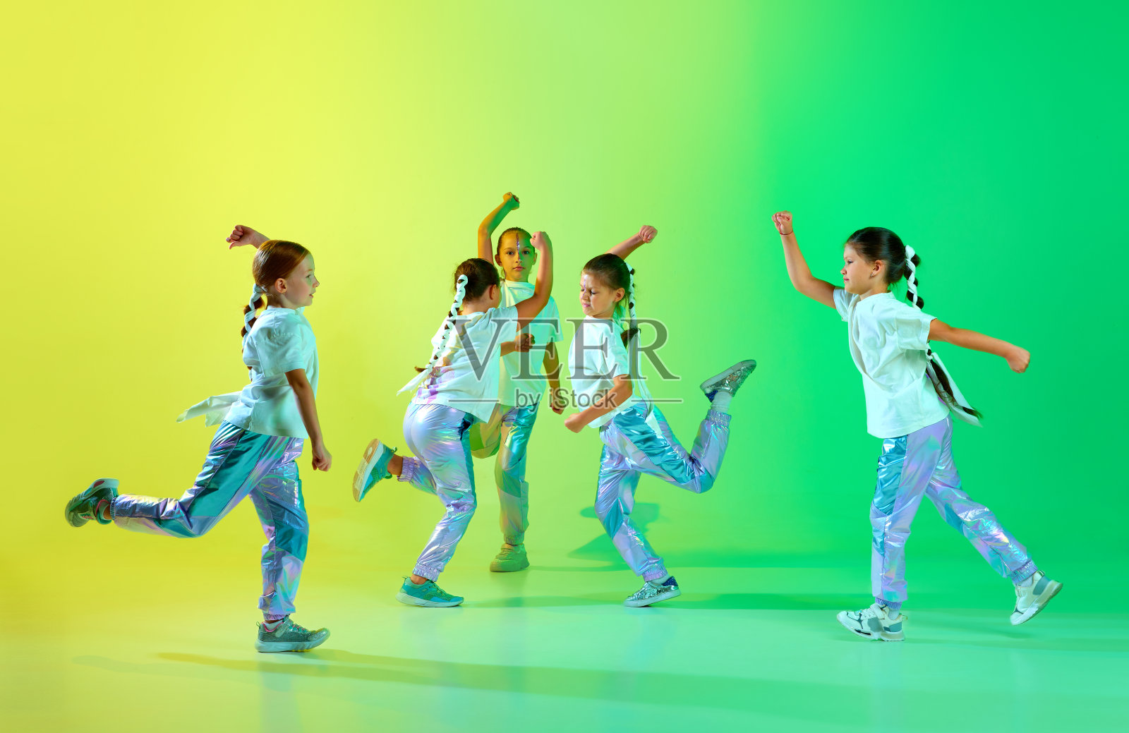 可爱的孩子们穿着时尚时髦的服装，亮闪闪的化妆表演新的舞蹈技巧，在渐变的背景下同步动作。照片摄影图片