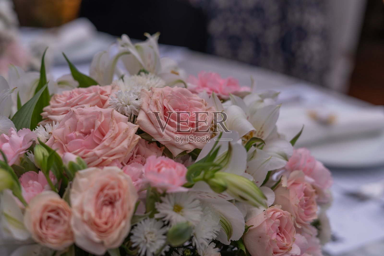 大理石午餐桌上摆放着玫瑰，白色的盘子和餐具放在模糊的背景中照片摄影图片