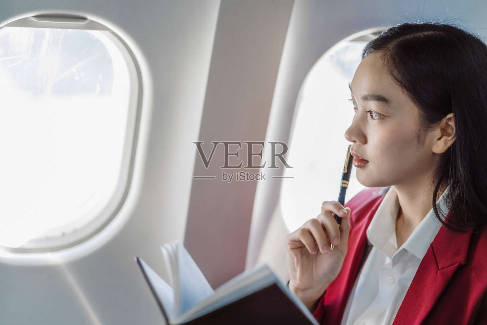 女性坐在飞机上工作和更新日历、日程、时间表、管理、活动策划。照片摄影图片