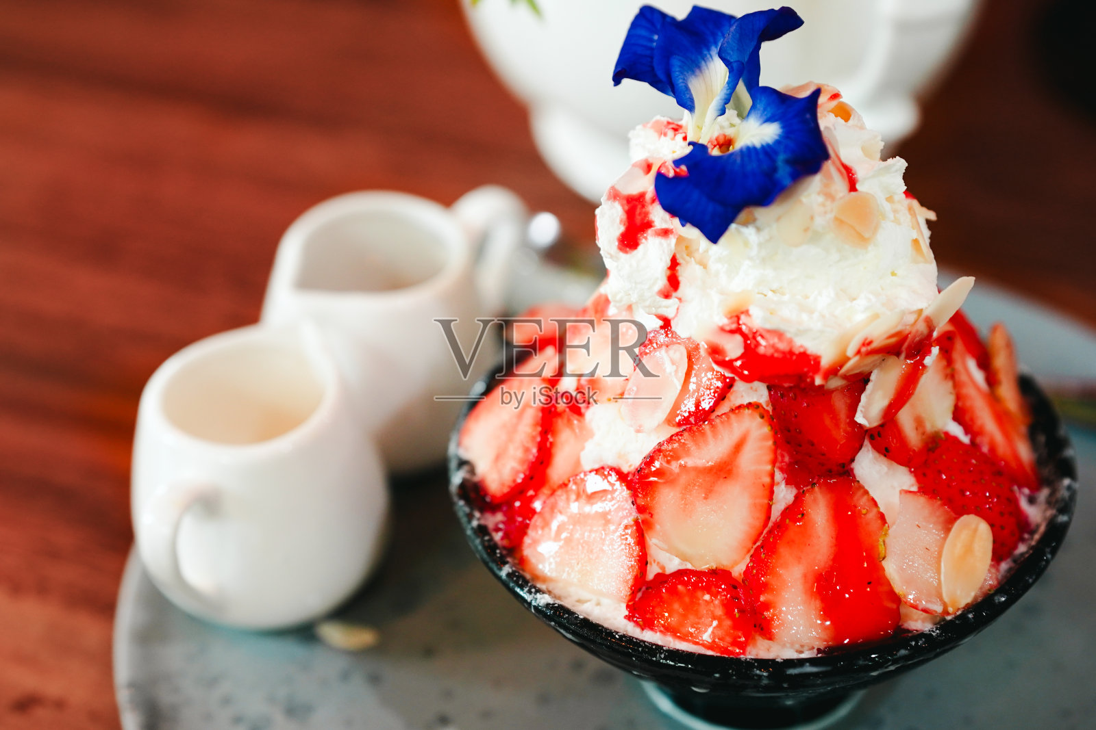 多汁的红草莓冰糕放在咖啡桌上的一个黑色杯子里，香甜可口。照片摄影图片