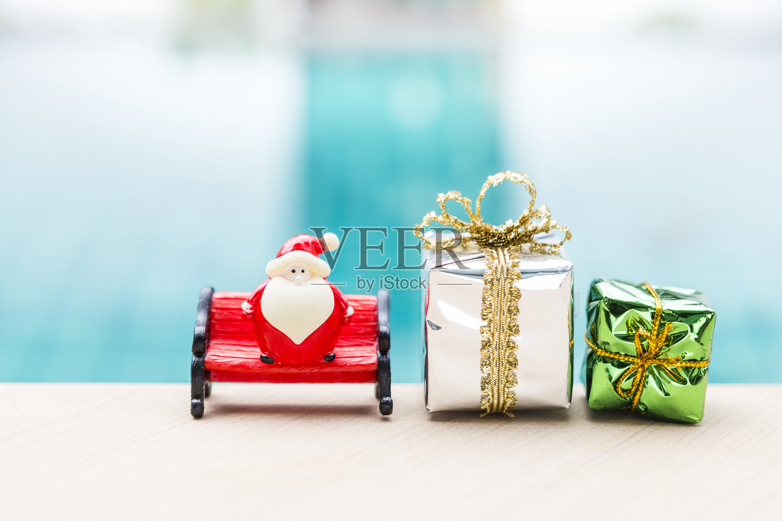 圣诞背景的想法，圣诞老人娃娃在红色的长凳与礼盒模糊的背景照片摄影图片