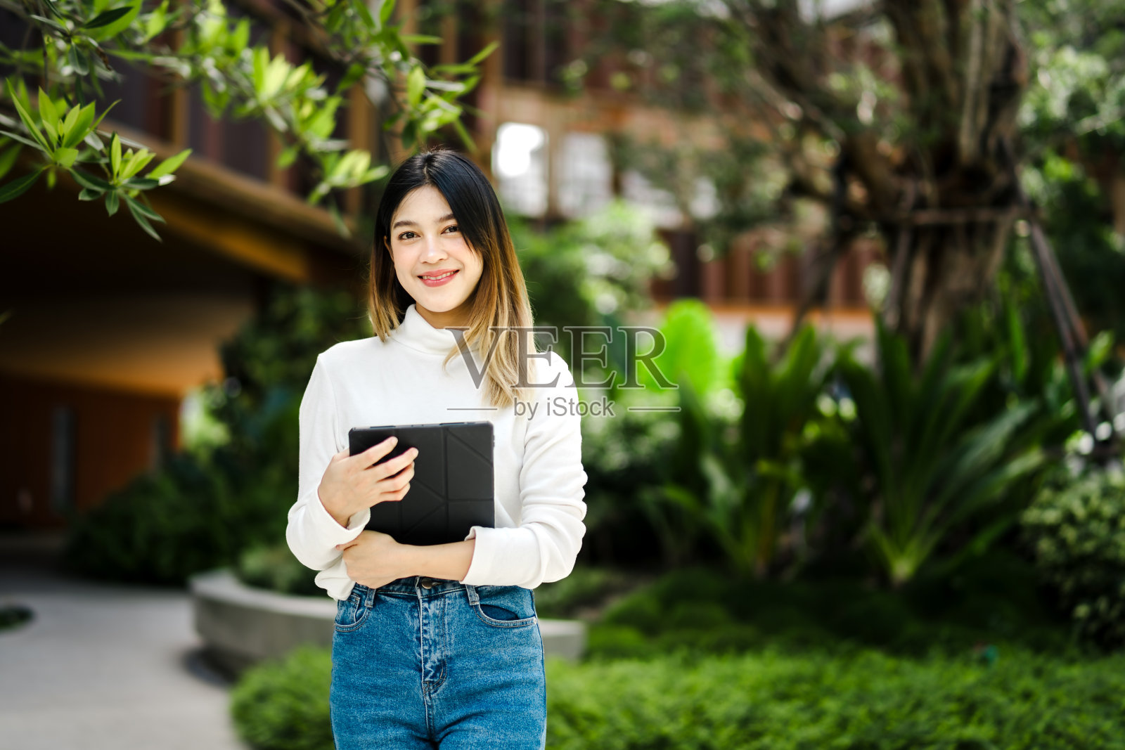 快乐的亚洲肖像美丽可爱的年轻女子站在数码平板电脑在大学照片摄影图片