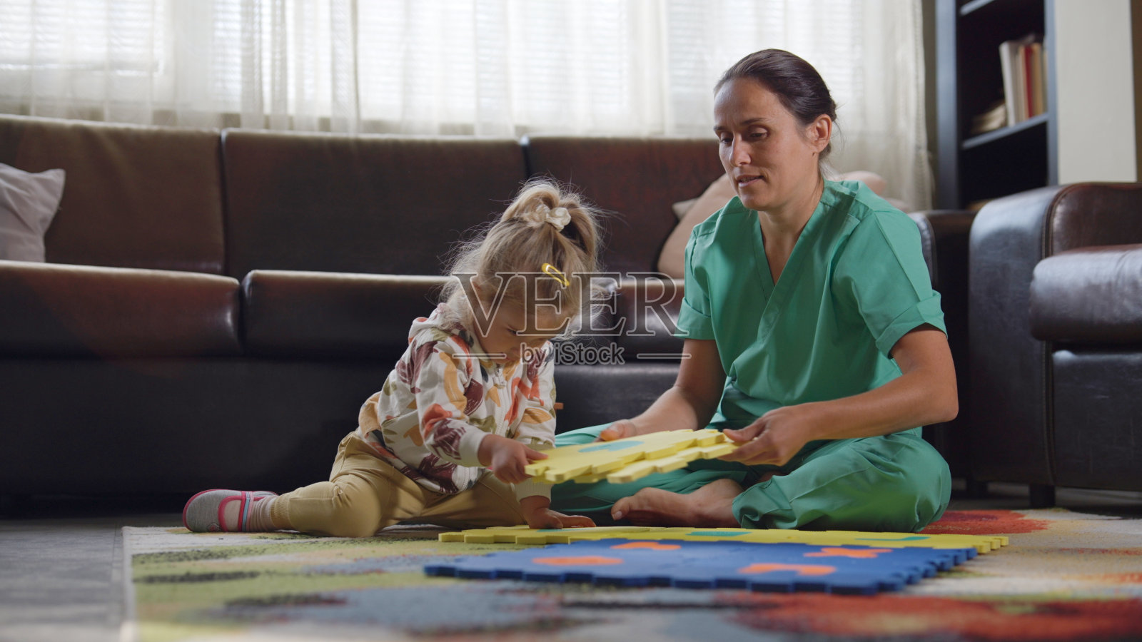 女卫生工作者在家中与女儿玩耍。穿着工作服的生活方式。照片摄影图片