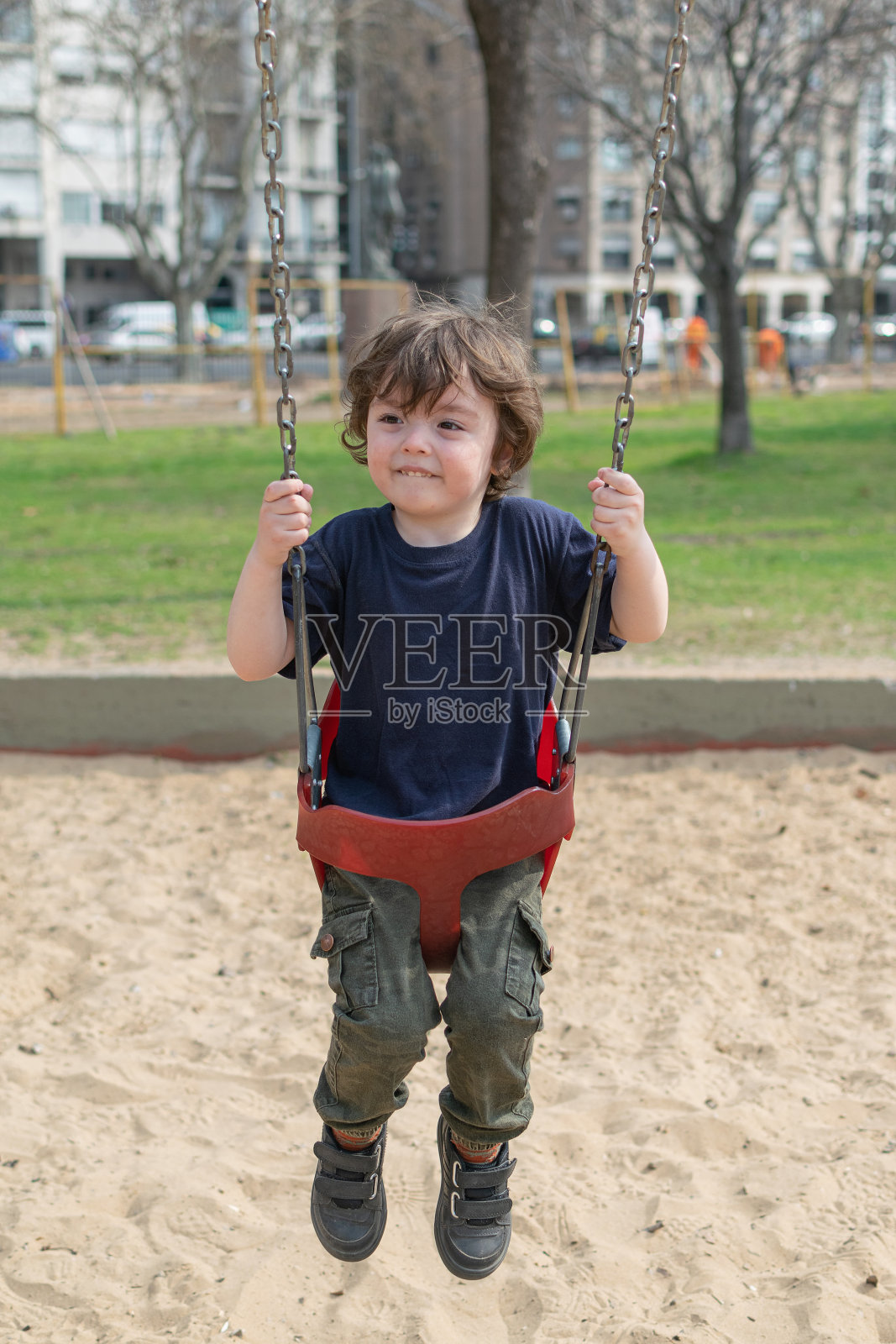 一个小孩子在操场上荡秋千照片摄影图片