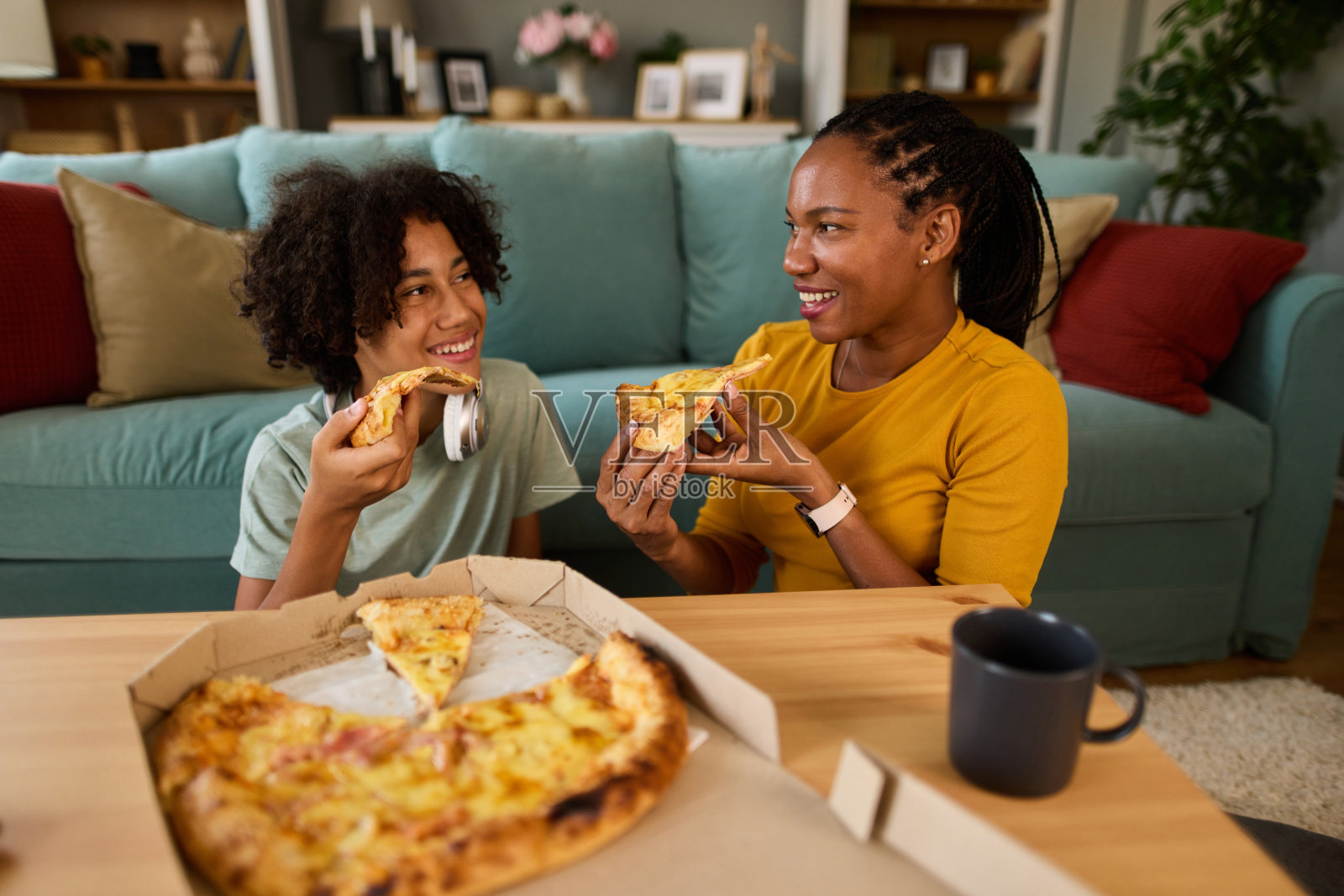 母亲和十几岁的儿子在家吃披萨照片摄影图片