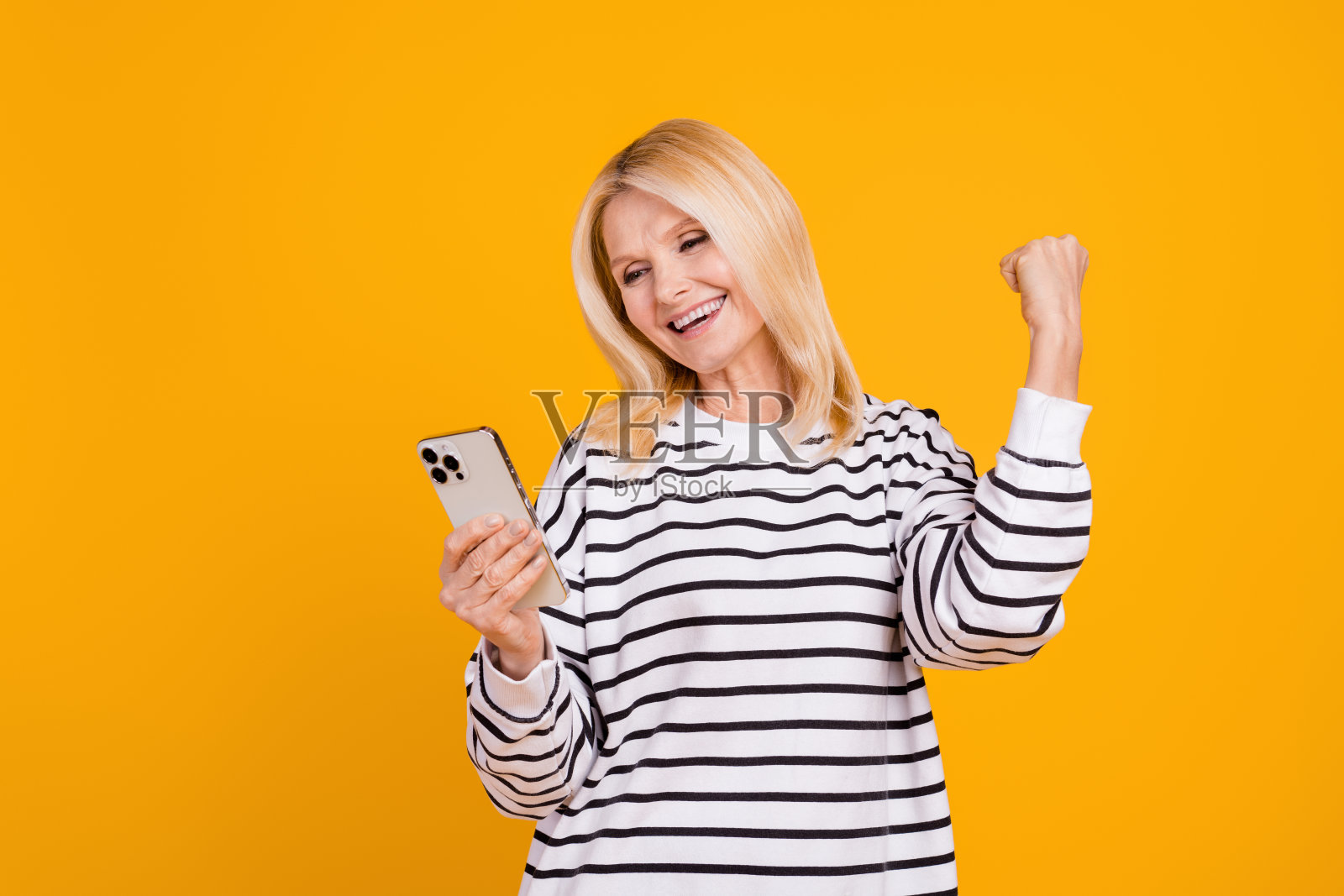 Photo of positive pensioner lady using device raise fists up achievements in social network isolated bright color background照片摄影图片