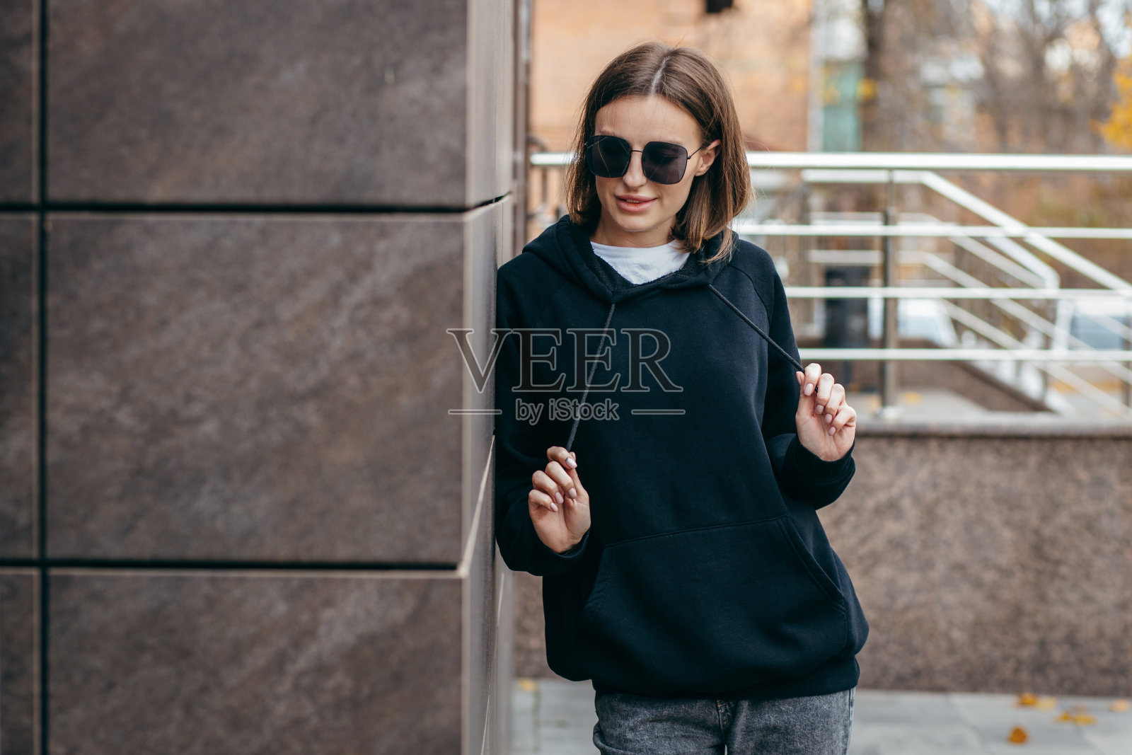 戴眼镜，穿黑色连帽衫的年轻女子照片摄影图片