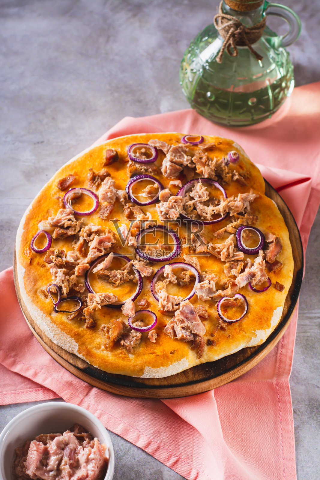 罐头金枪鱼和洋葱在烤披萨上的木板上的桌子上垂直观看照片摄影图片