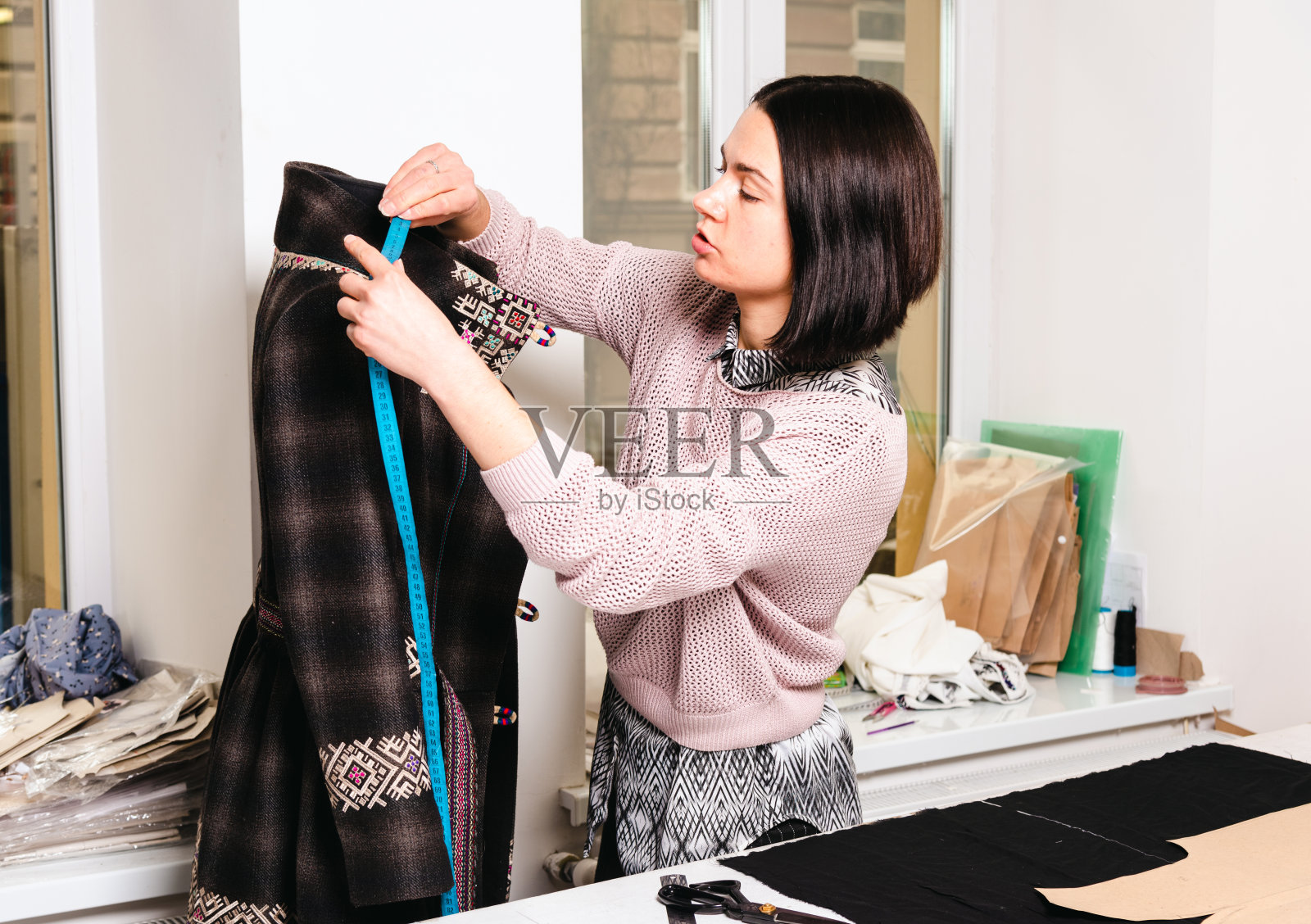 女裁缝在裁缝车间工作，桌子上放着布料和工具照片摄影图片