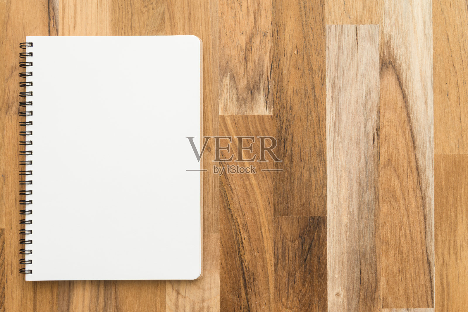 在木桌背景上平铺开着的空白螺旋记事本或笔记本。照片摄影图片