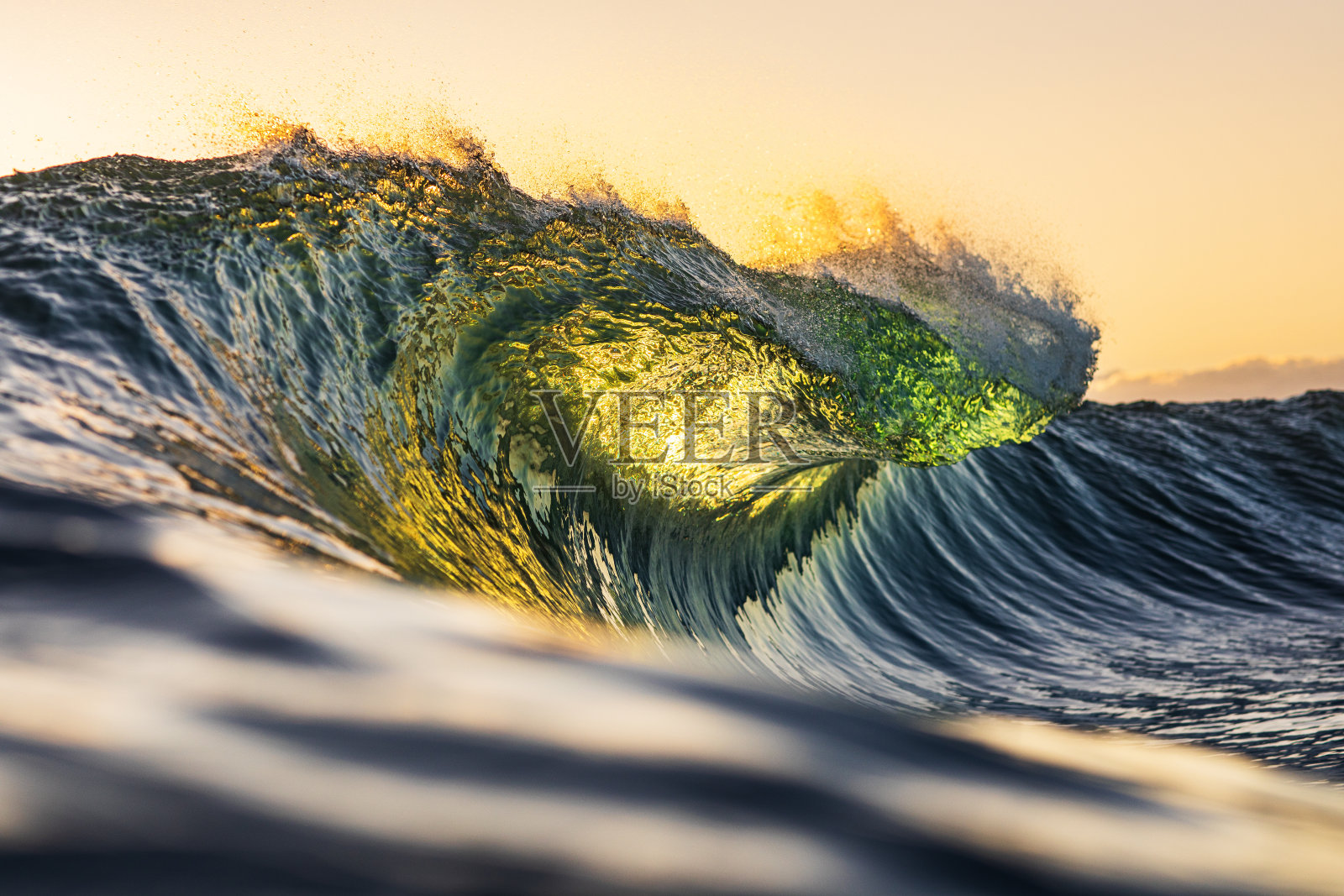 在温暖的晨光下，海浪在海洋中破碎照片摄影图片